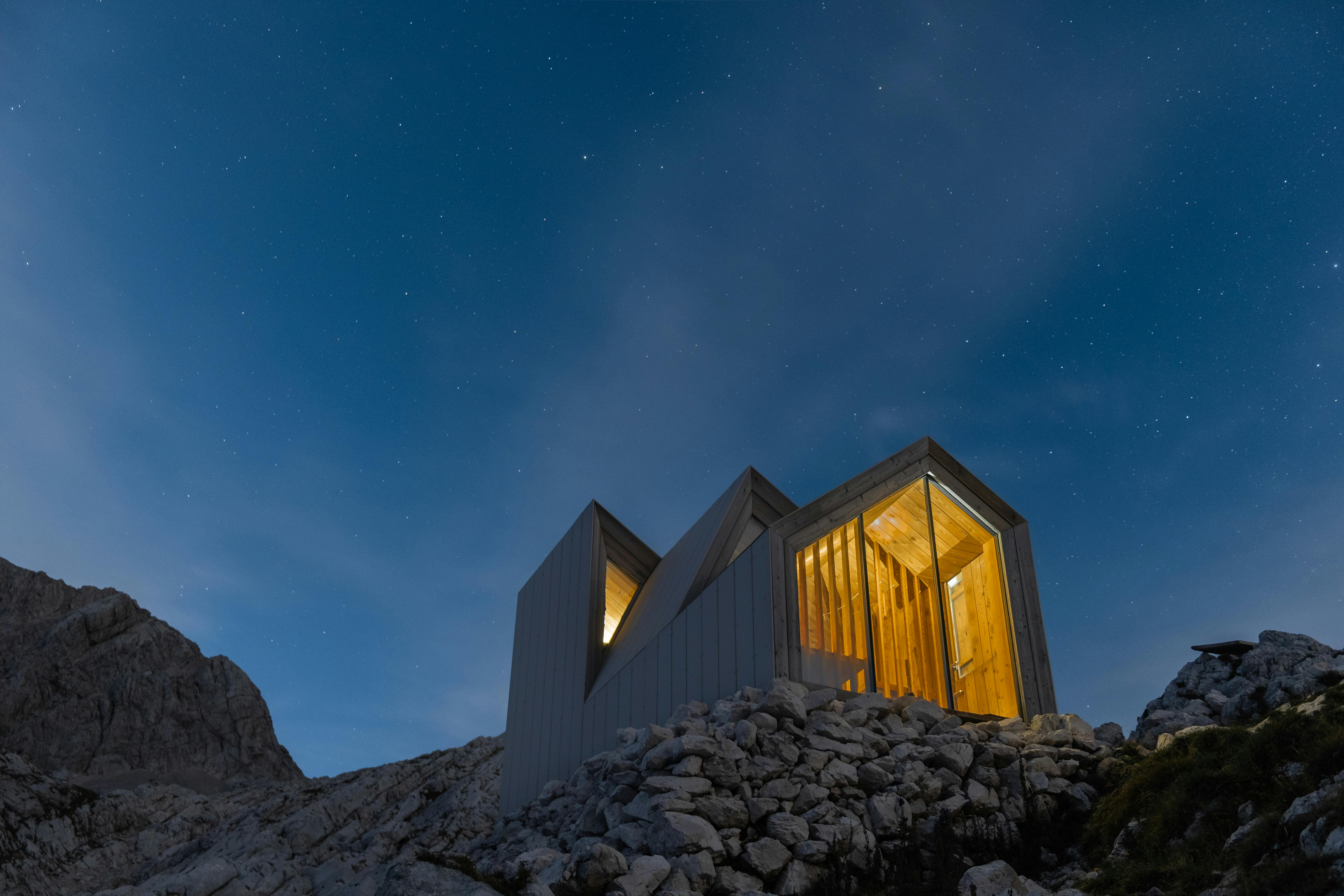 A minimalist contemporary small house perched on top of a hill in Kranj, Slovenia, offering a stunning view of the surrounding landscape.