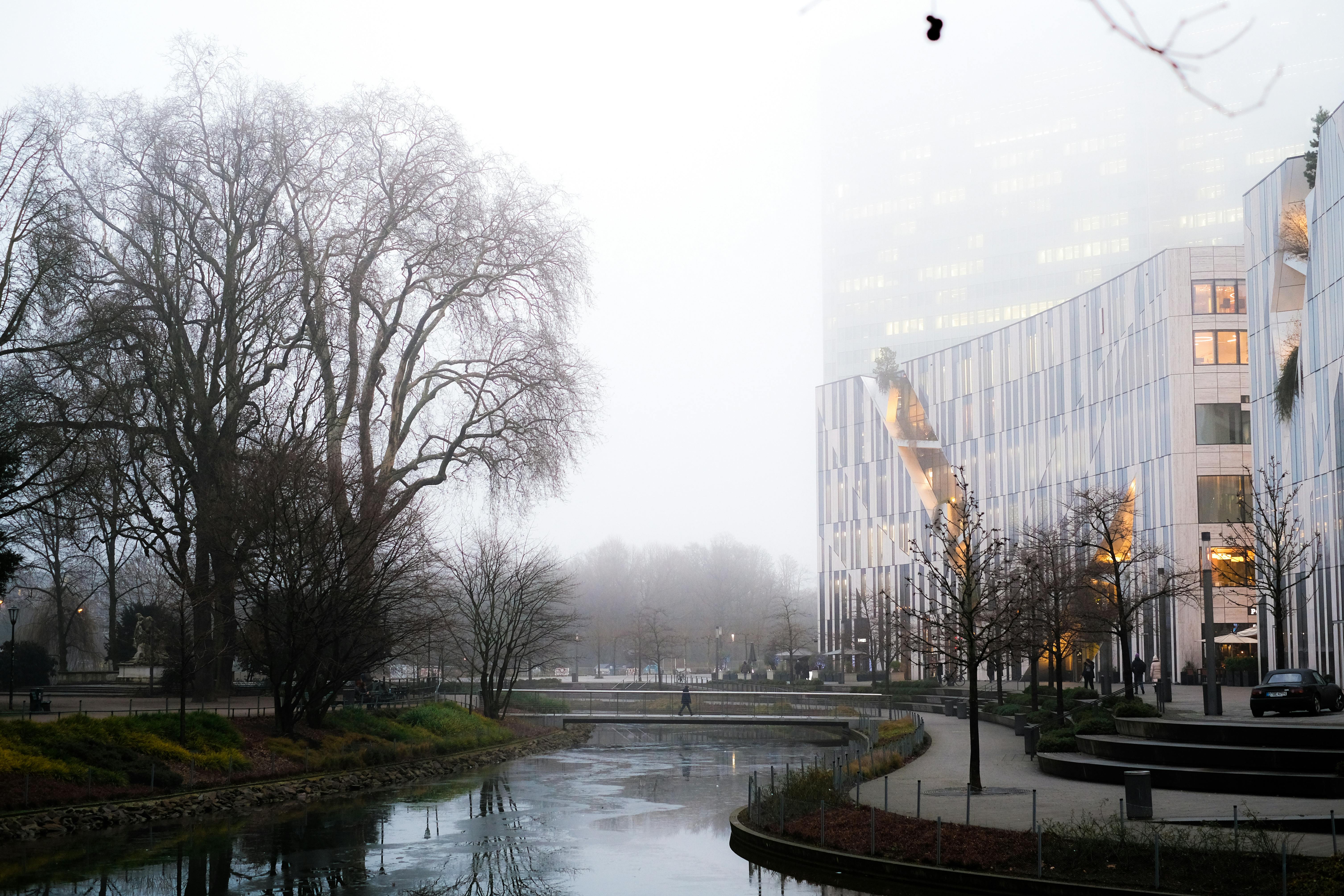 A modern building stands amidst a foggy winter landscape, surrounded by mist and snow-covered terrain.