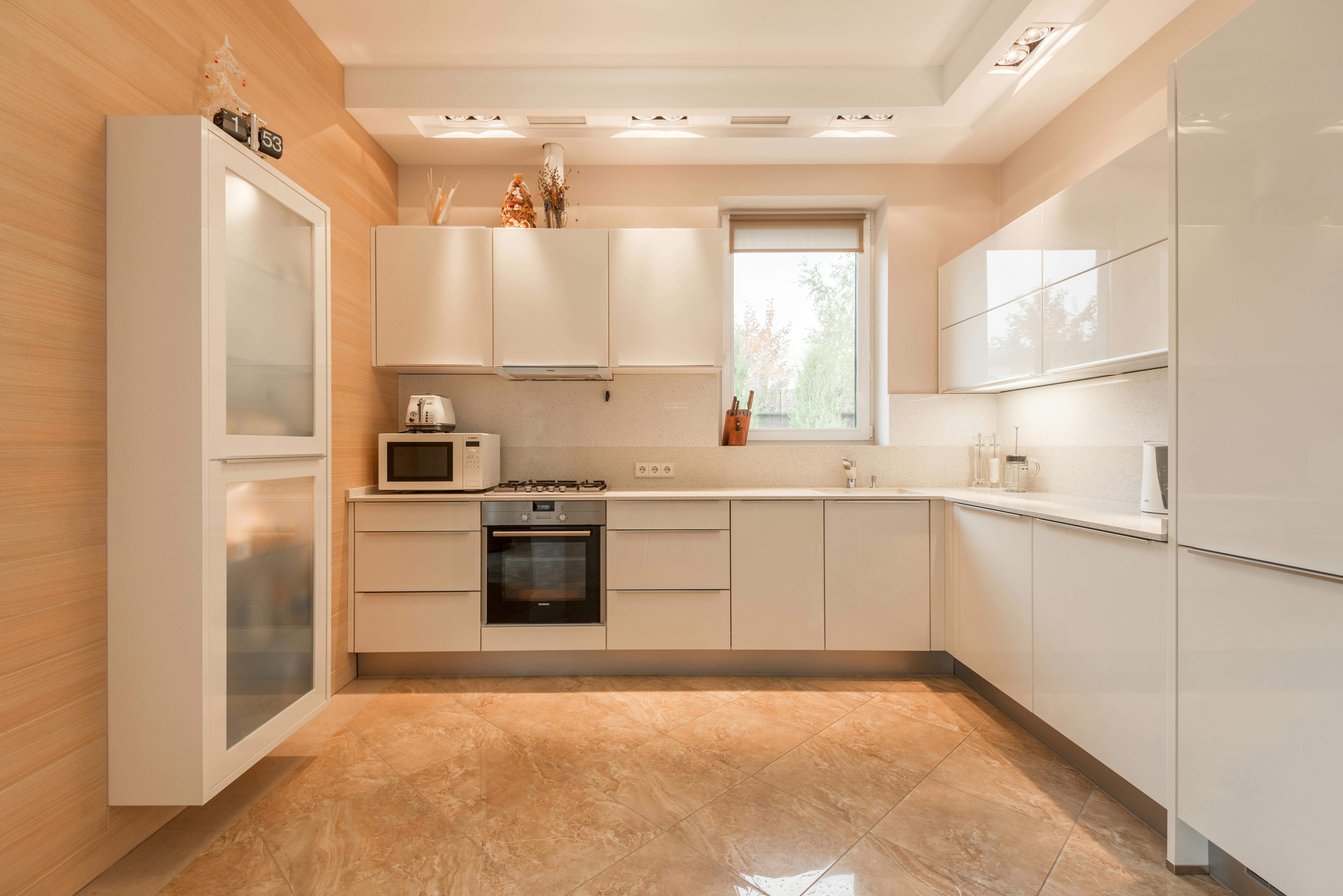 Minimalist kitchen with glossy cream cabinets, featuring a sleek and modern design.