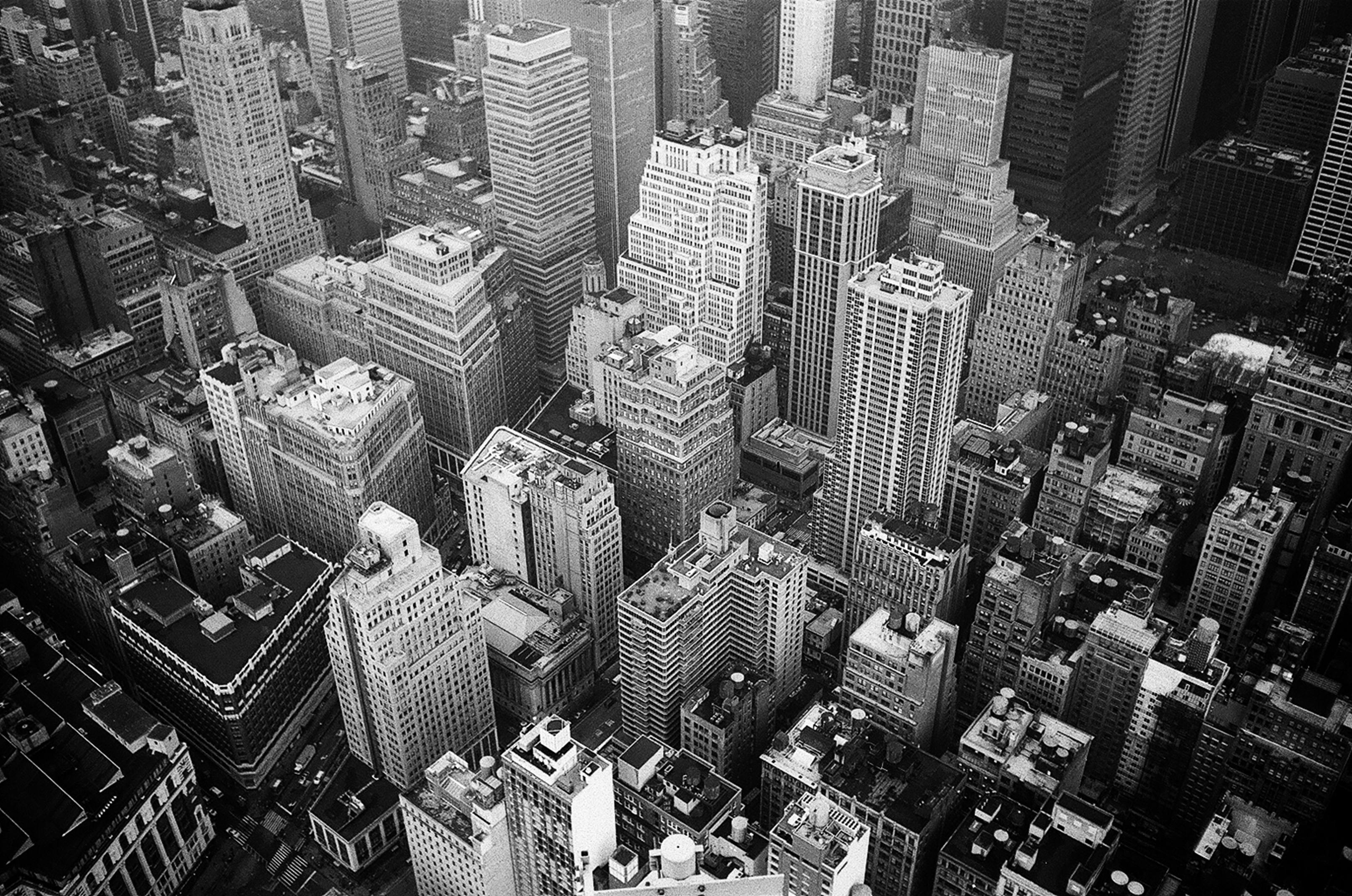 Aerial grayscale photograph of New York's high-rise buildings, emphasizing their urban scale.