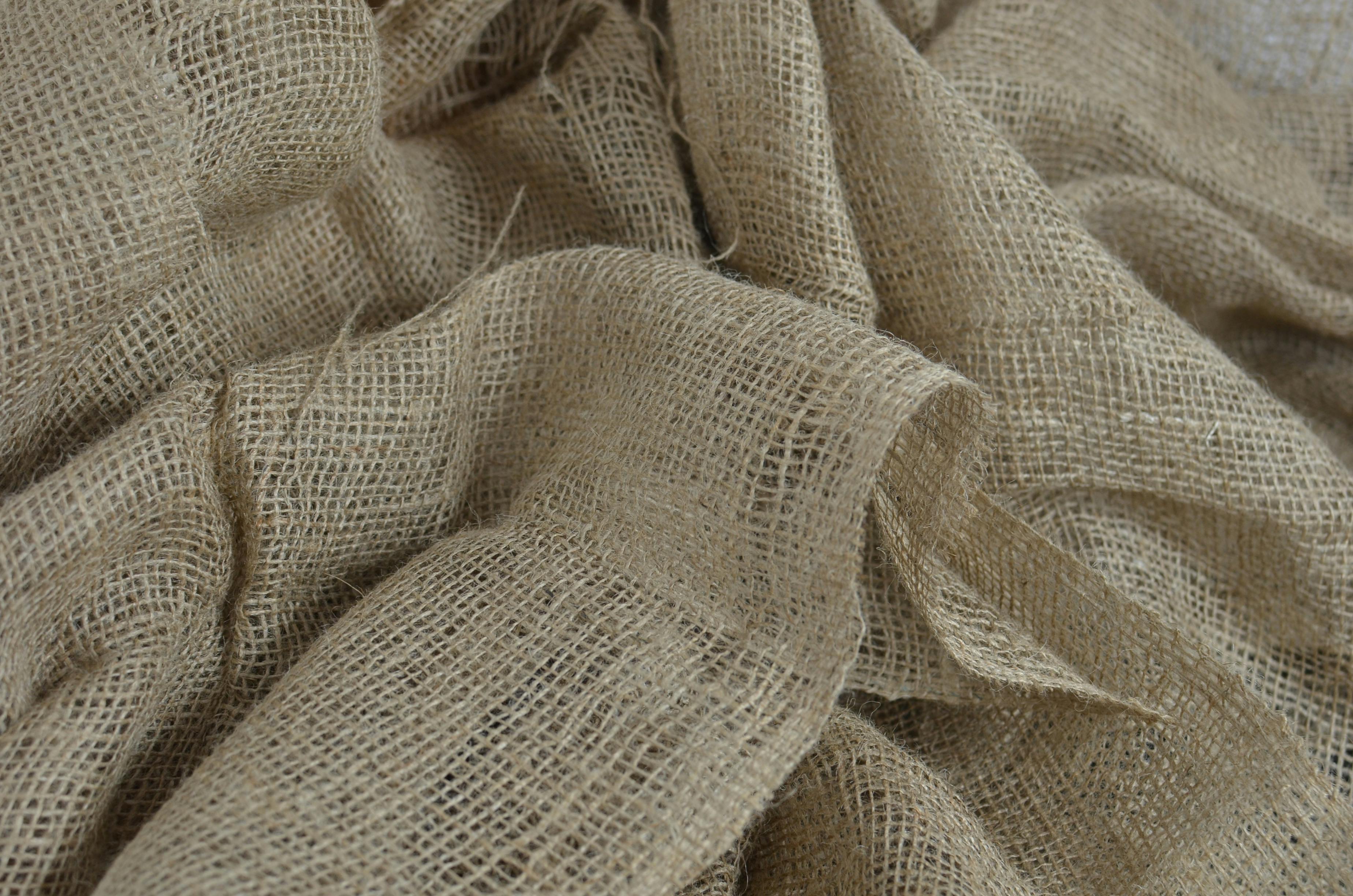 Textured background of organic sackcloth burlap with tiny holes, showcasing its natural weave and structure.
