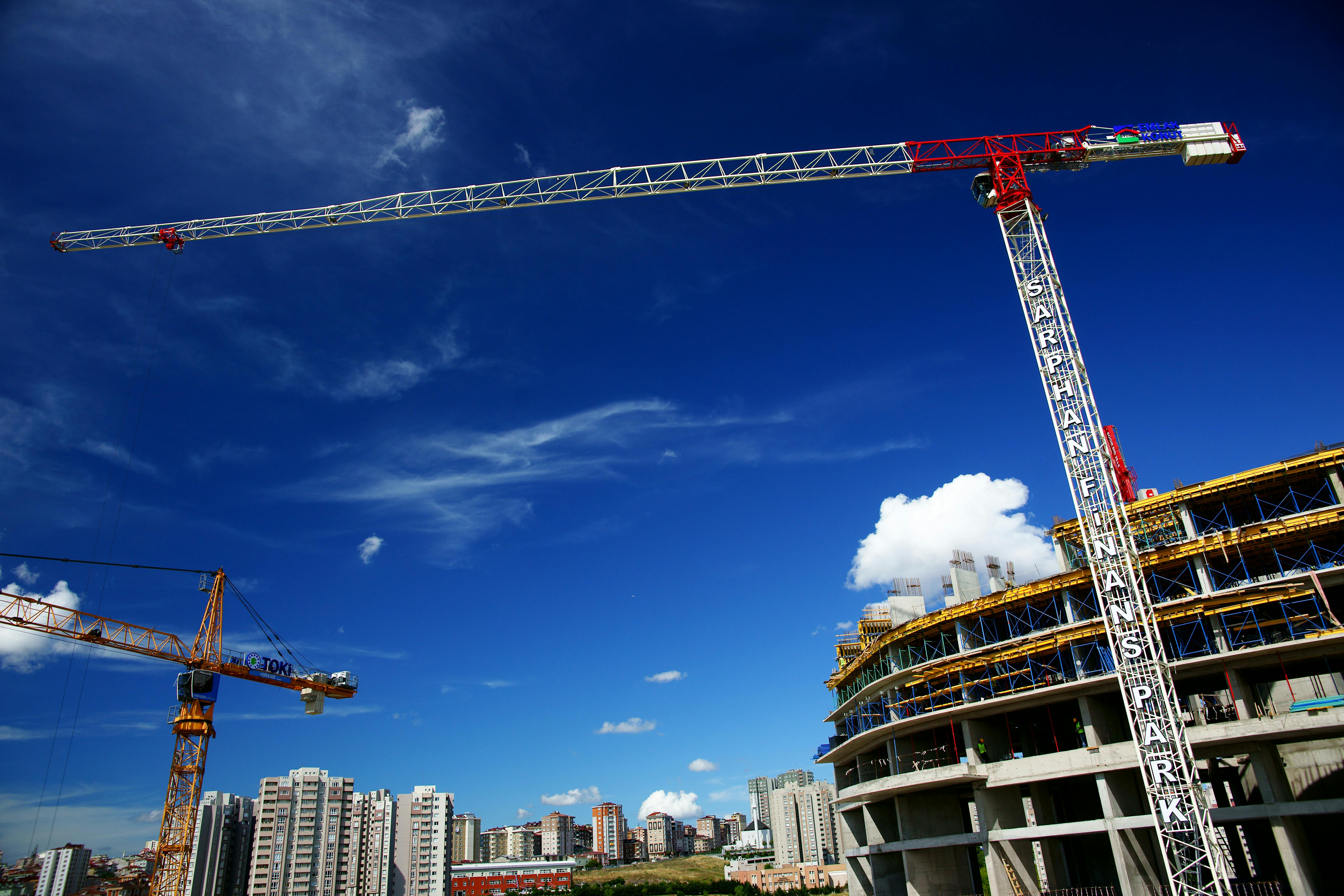 Tower crane at a construction site lifting materials with a clear sky in the background.