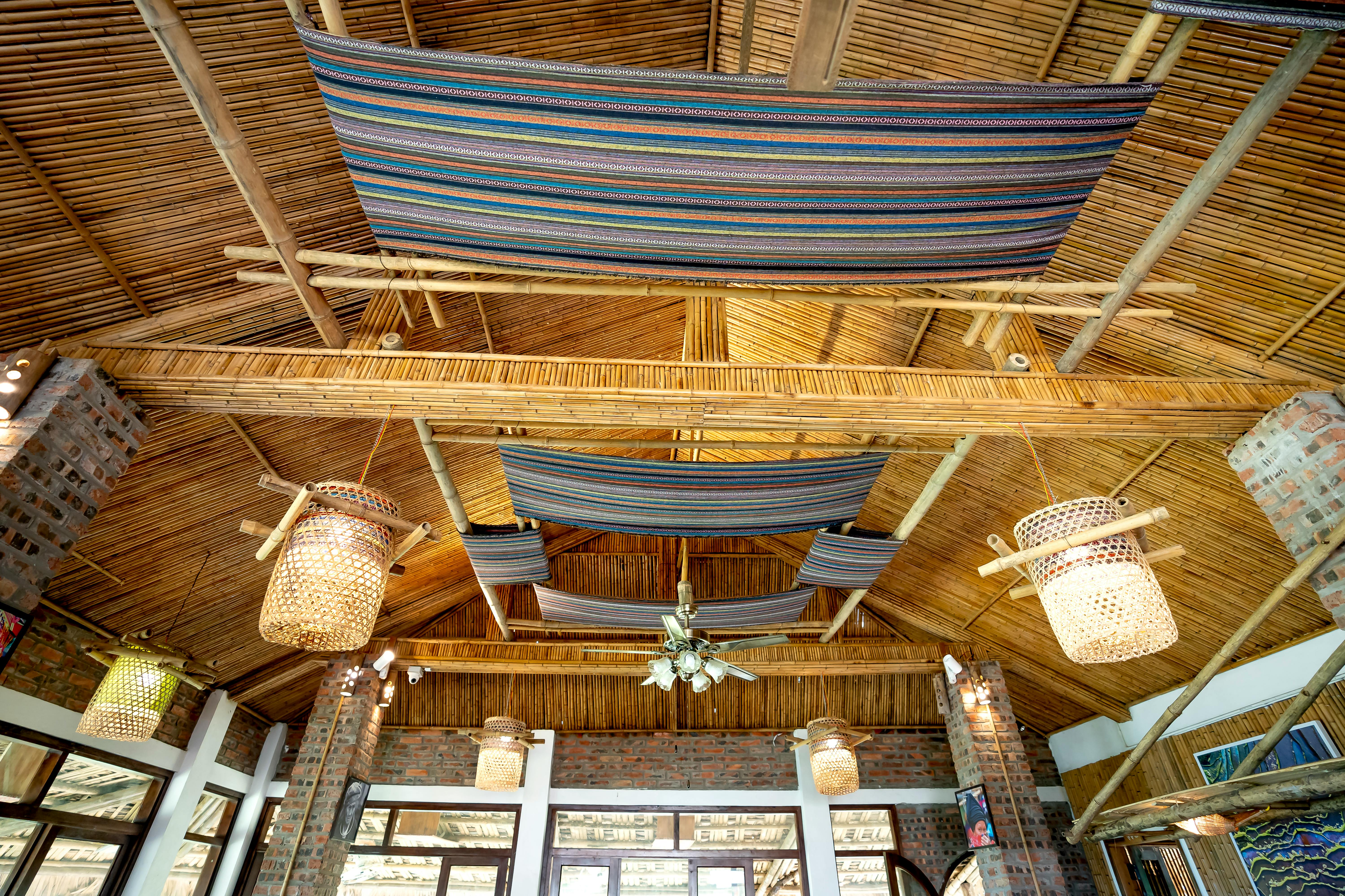 Interior of a traditional cafe with a mud and bamboo roof, featuring rustic and natural elements.