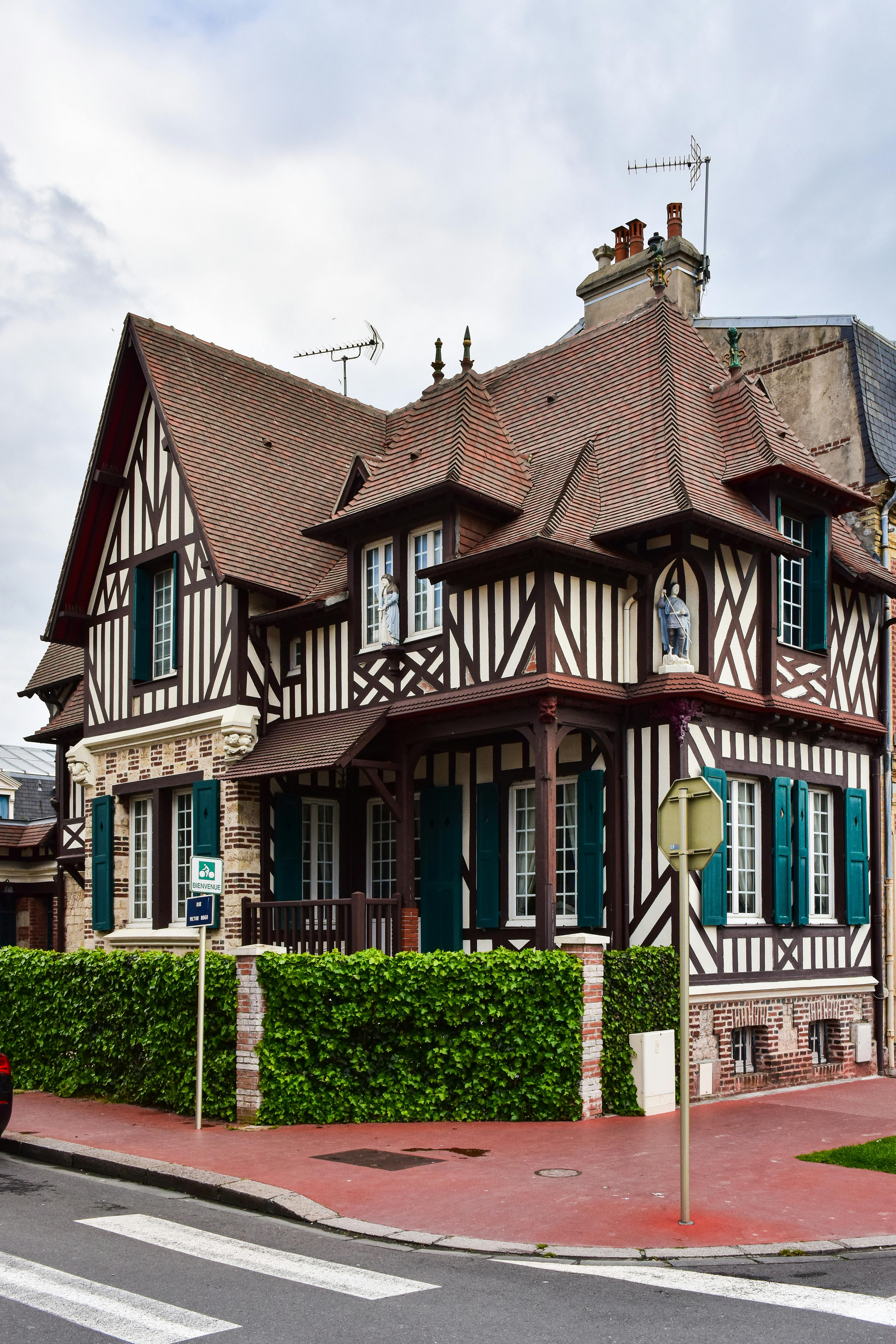 Picturesque Tudor-style half-timbered house with green shutters and a white roof in Deauville, France.