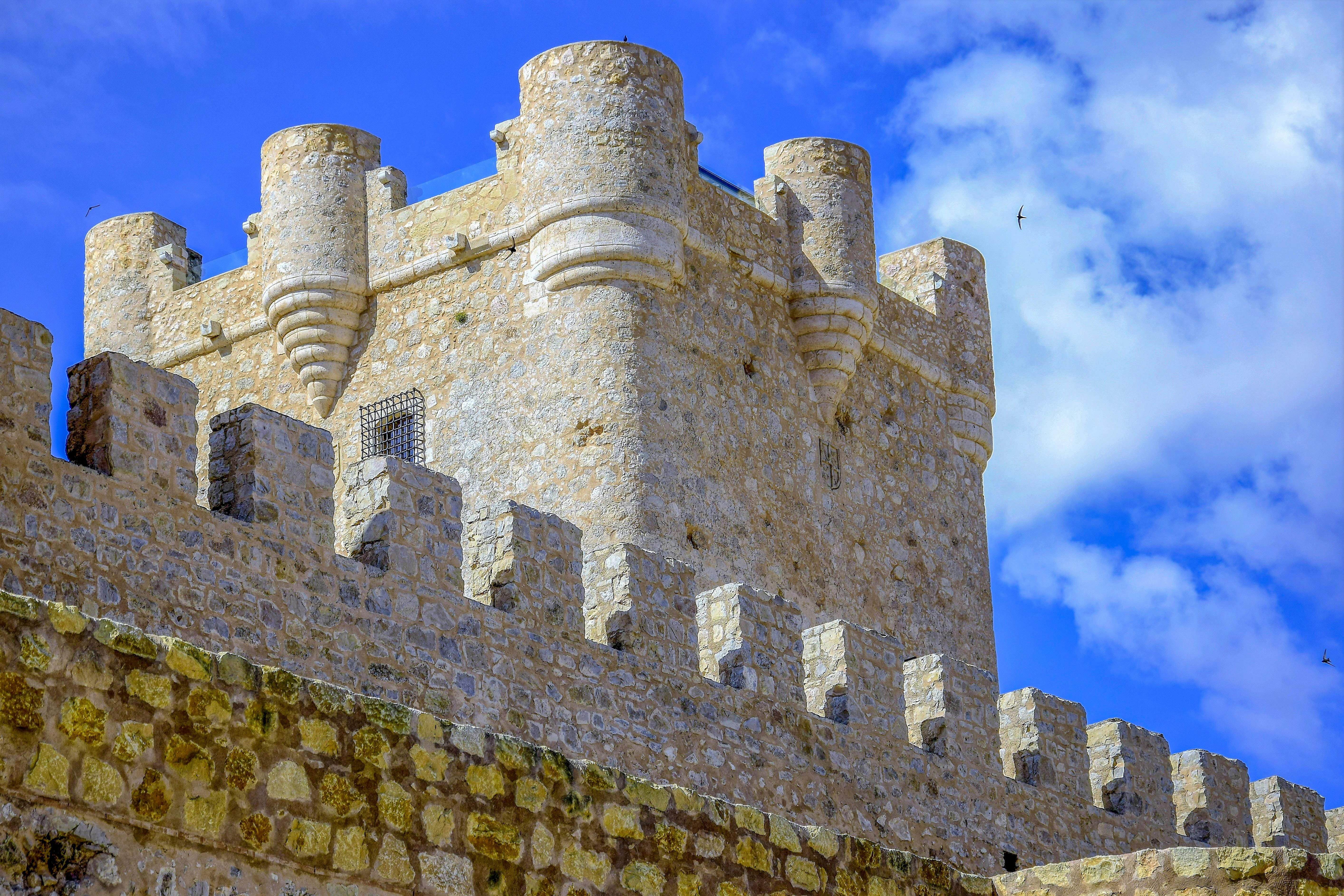 Medieval military castle wall and tower in Villena, Spain, built with stone battlements for defense.