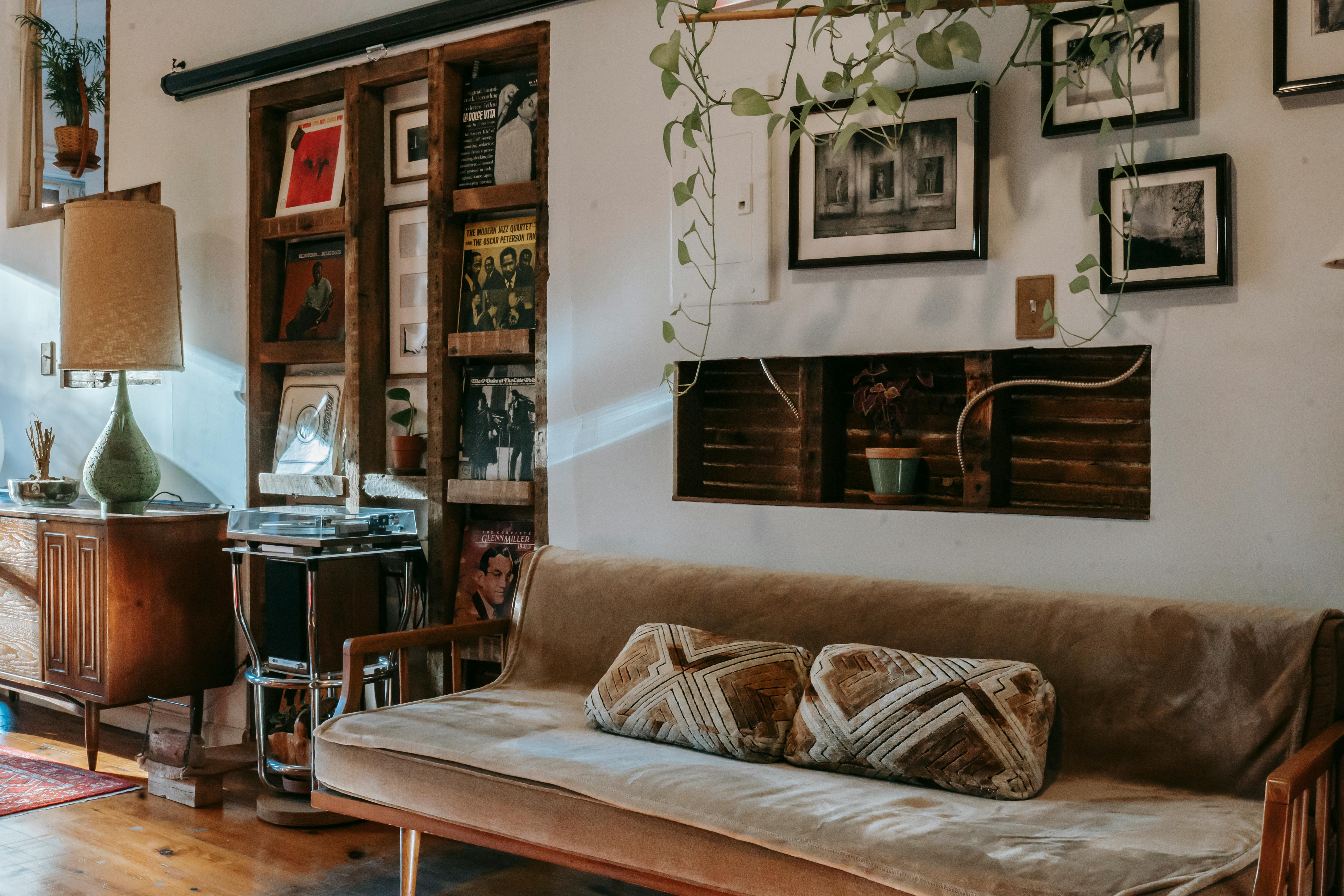 Shelf with vinyl records collection placed between a comfortable sofa and wooden cabinet in a vintage-styled room.