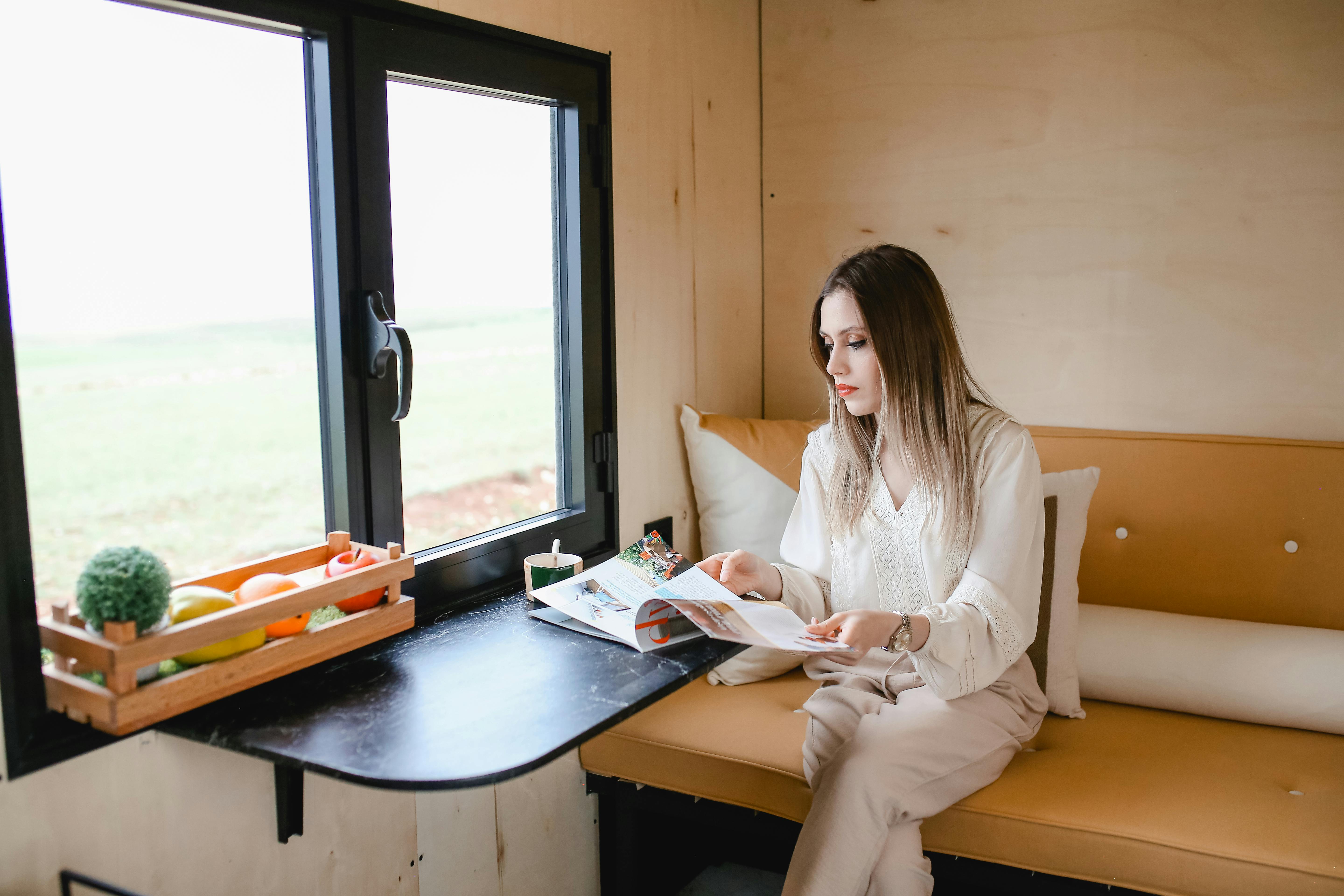 Woman sitting inside a modern mobile home, enjoying the comfortable and stylish interior.