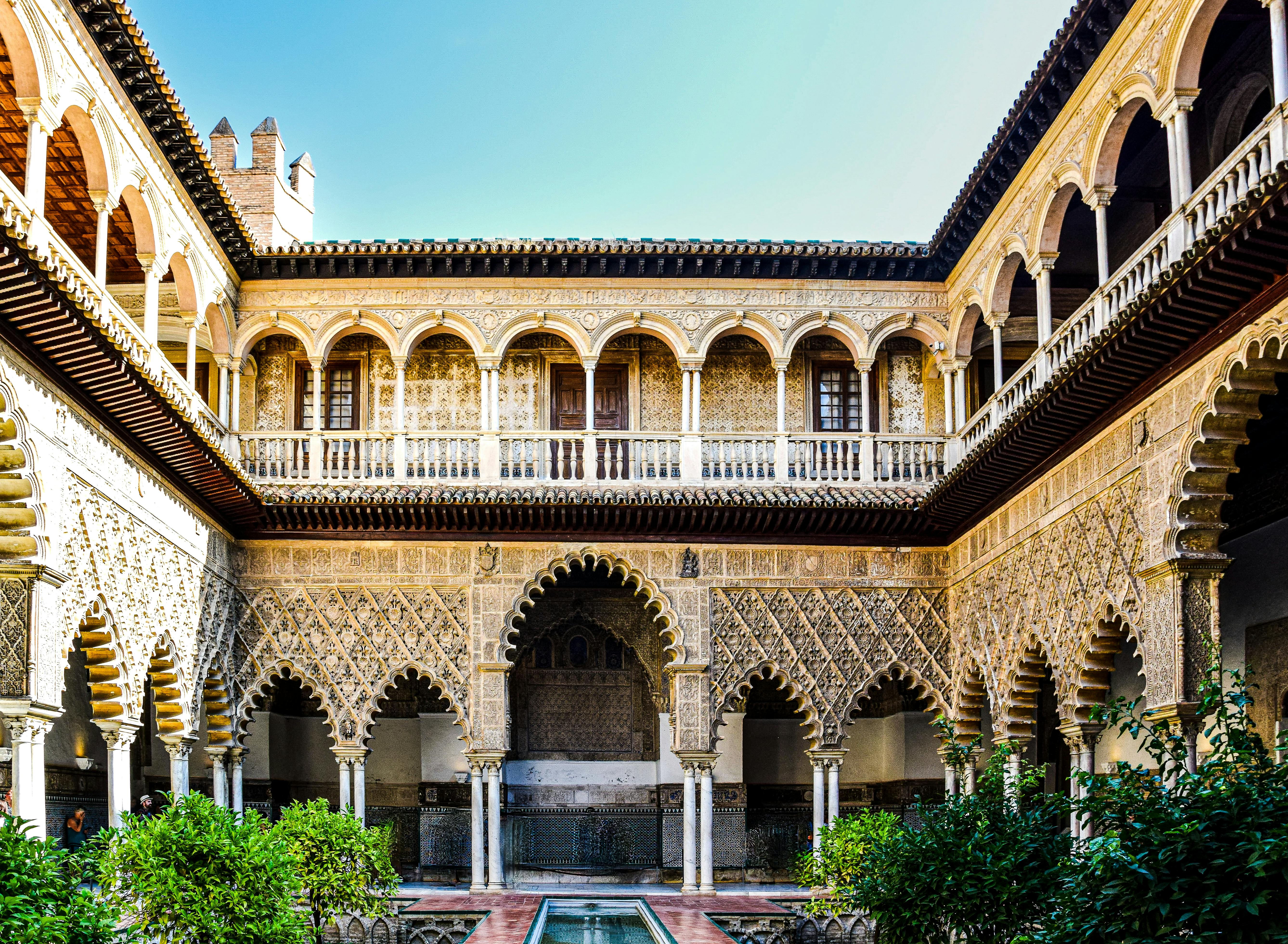 Courtyard of the Alcazar in Seville with Moorish arches and tiled walls.