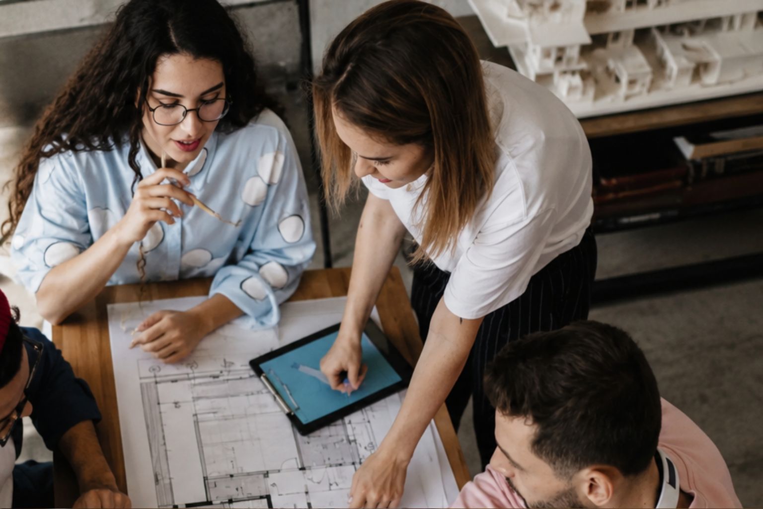 Architecture students reviewing blueprints and design drawings on a studio table during an architecture school project.