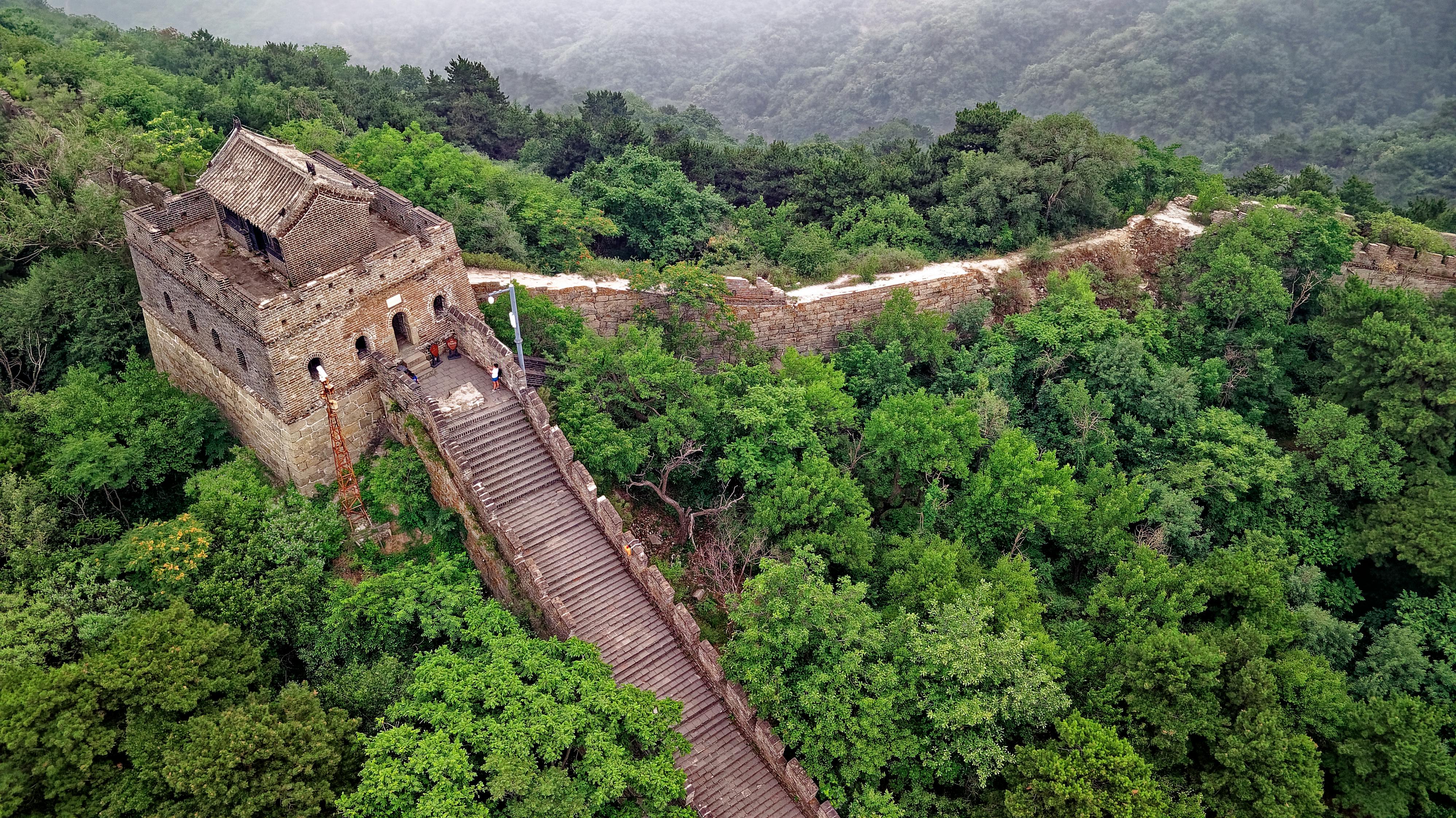 Watchtower on forested Great Wall section.