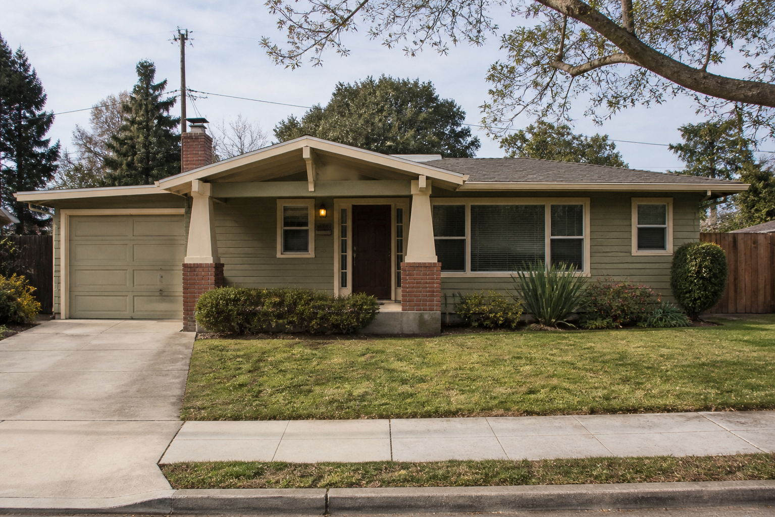 1950s Craftsman-influenced ranch house with low roofline, front porch, attached garage, and wide windows.