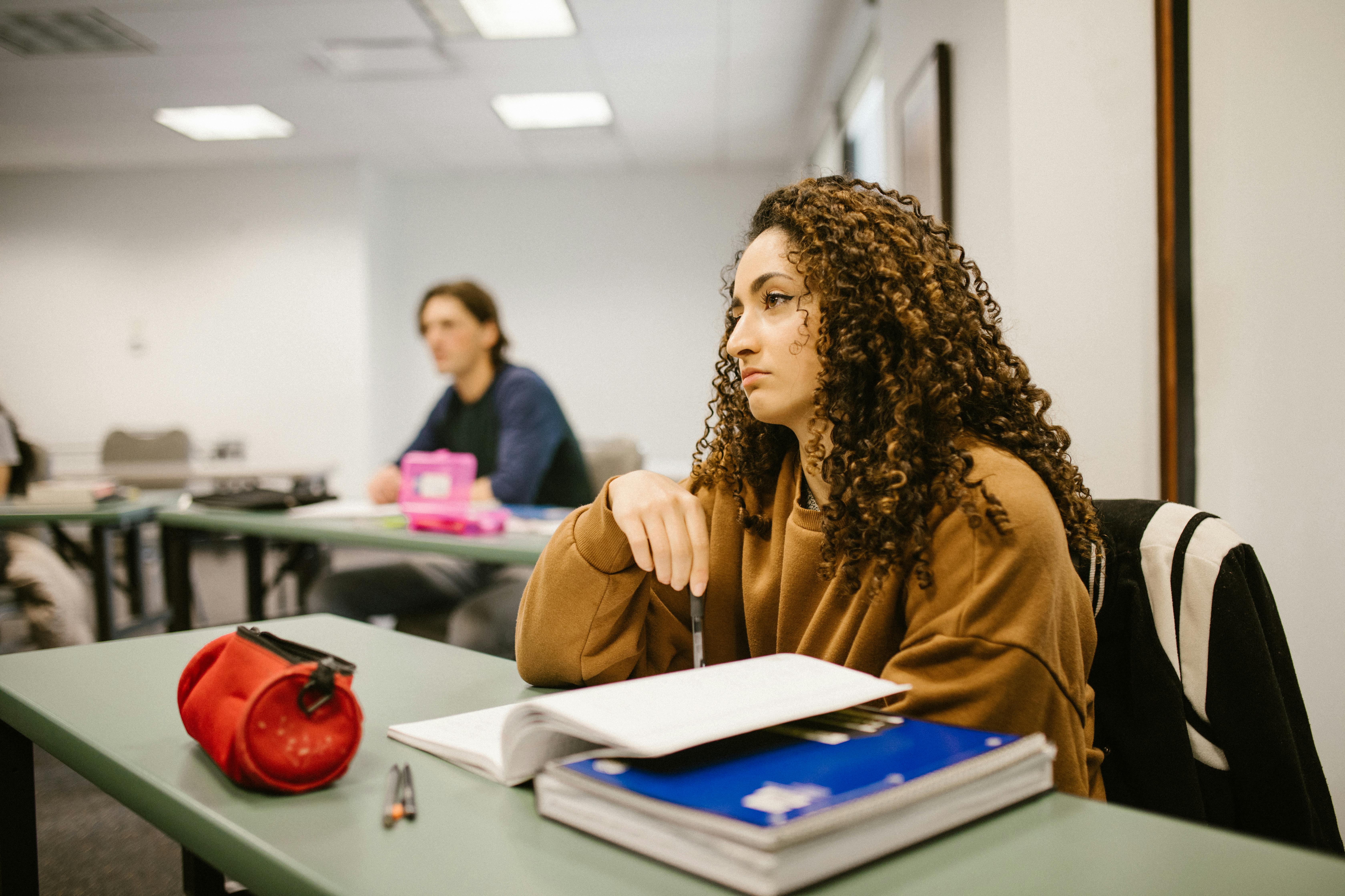 A student with a downcast expression sits in an architecture classroom, reflecting the challenges of traditional learning methods in architectural education.