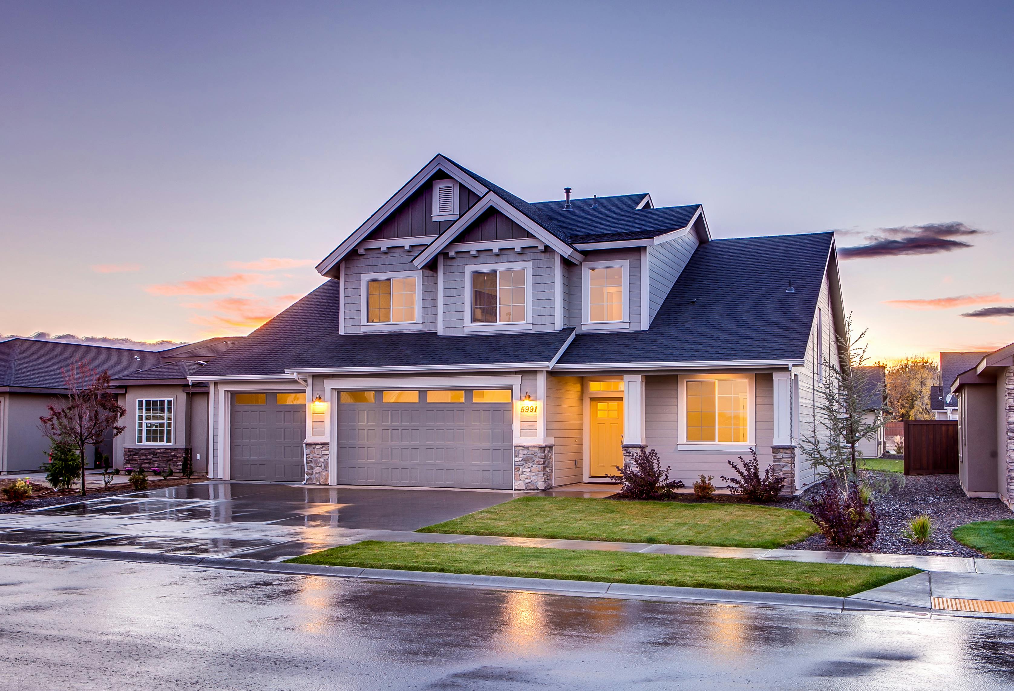Blue and gray concrete house facade with attic and visible lighting details.