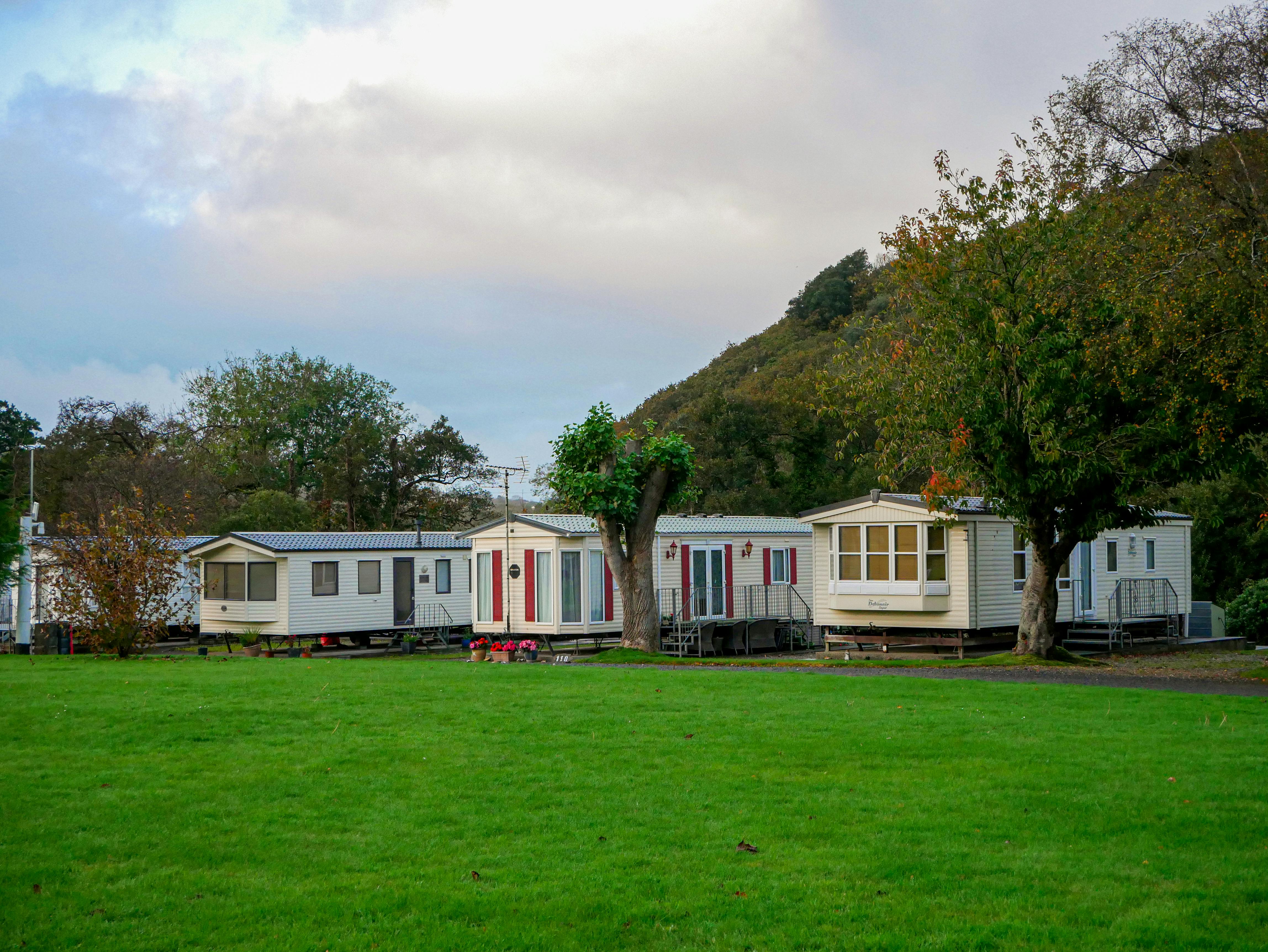 Single-wide mobile homes in a peaceful countryside setting.