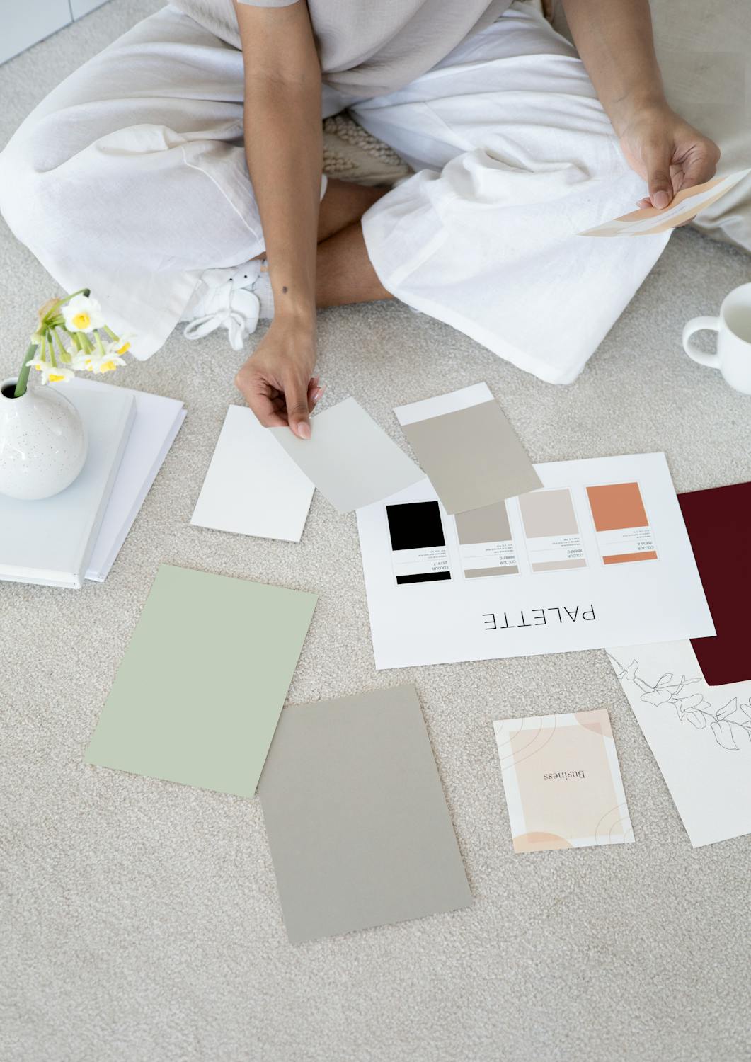 Woman selecting a simple neutral color palette with soft earthy tones for home design.