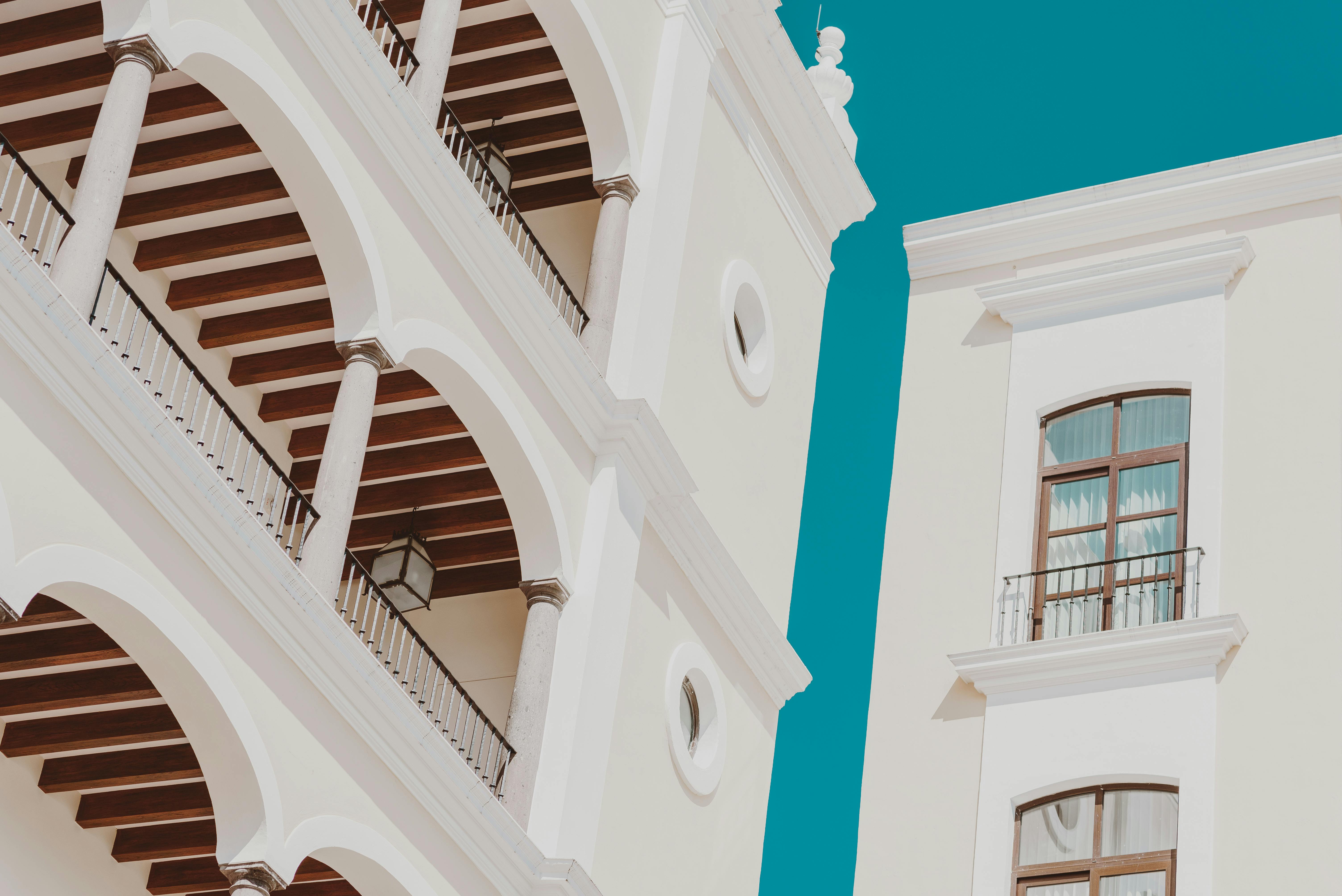 Hacienda-style windows with arched tops, wooden frames, wrought iron grilles, and functional shutters.