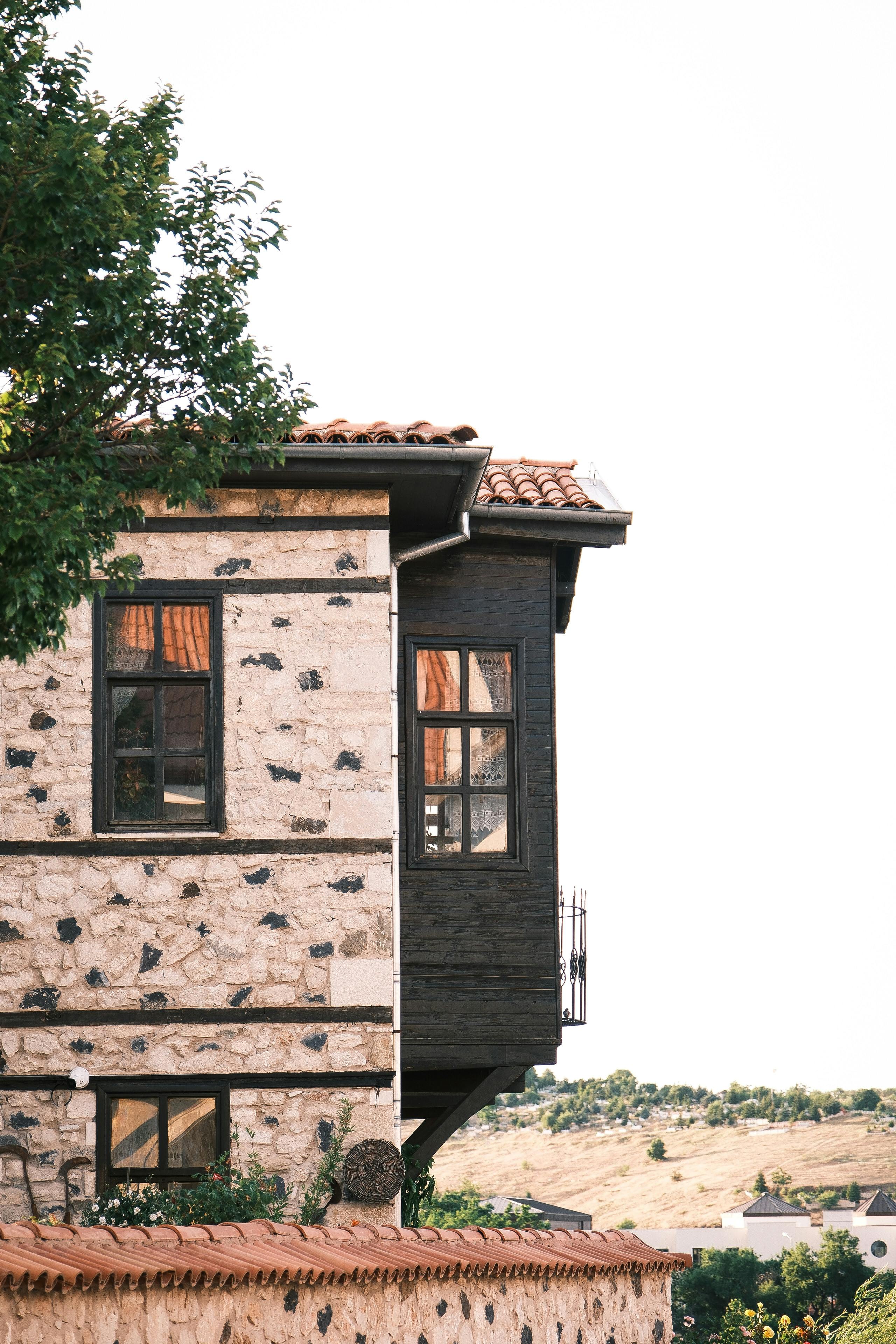 Half-timbered stone house in sunny rural setting.