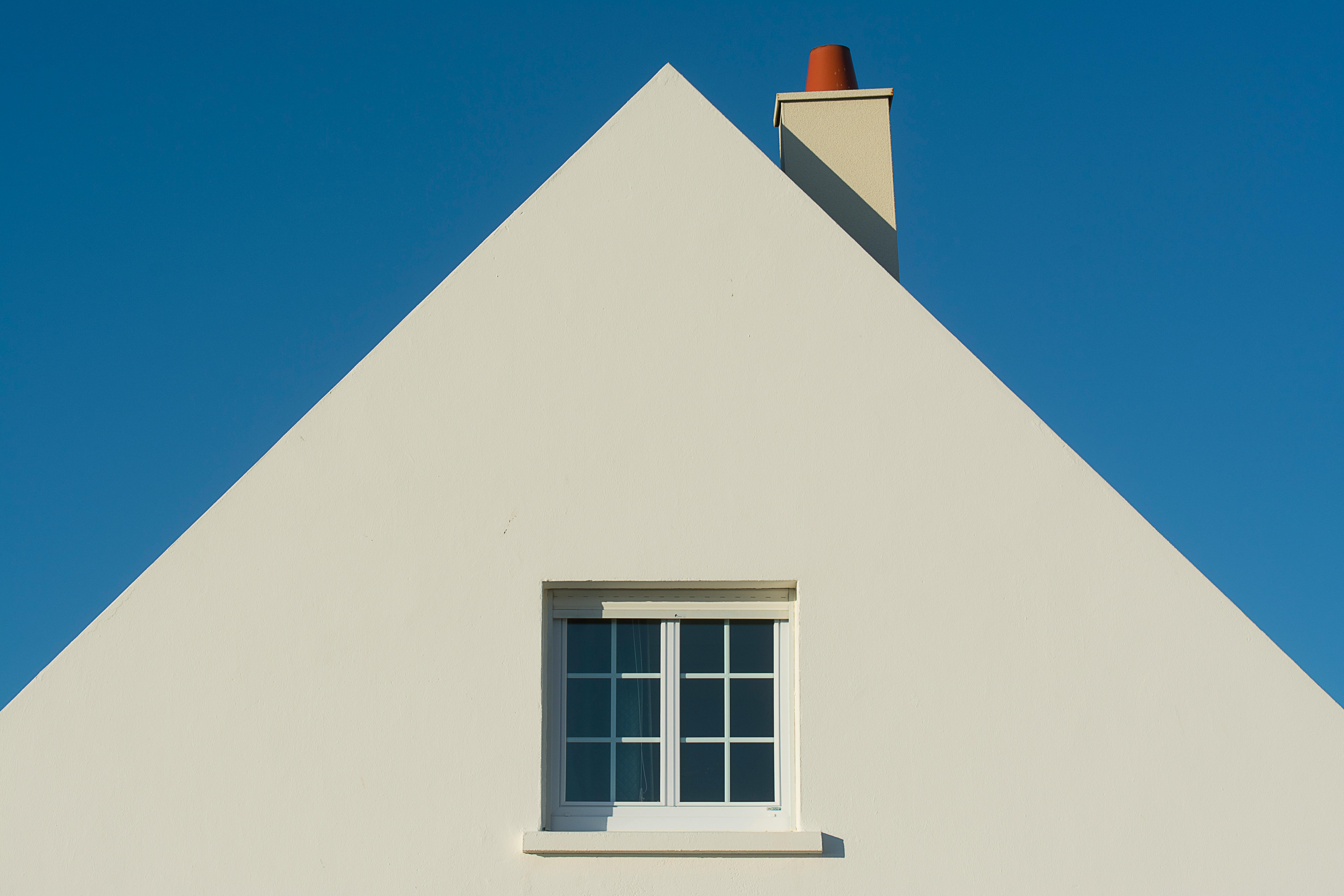 A-frame house with simple white facade and attic window.