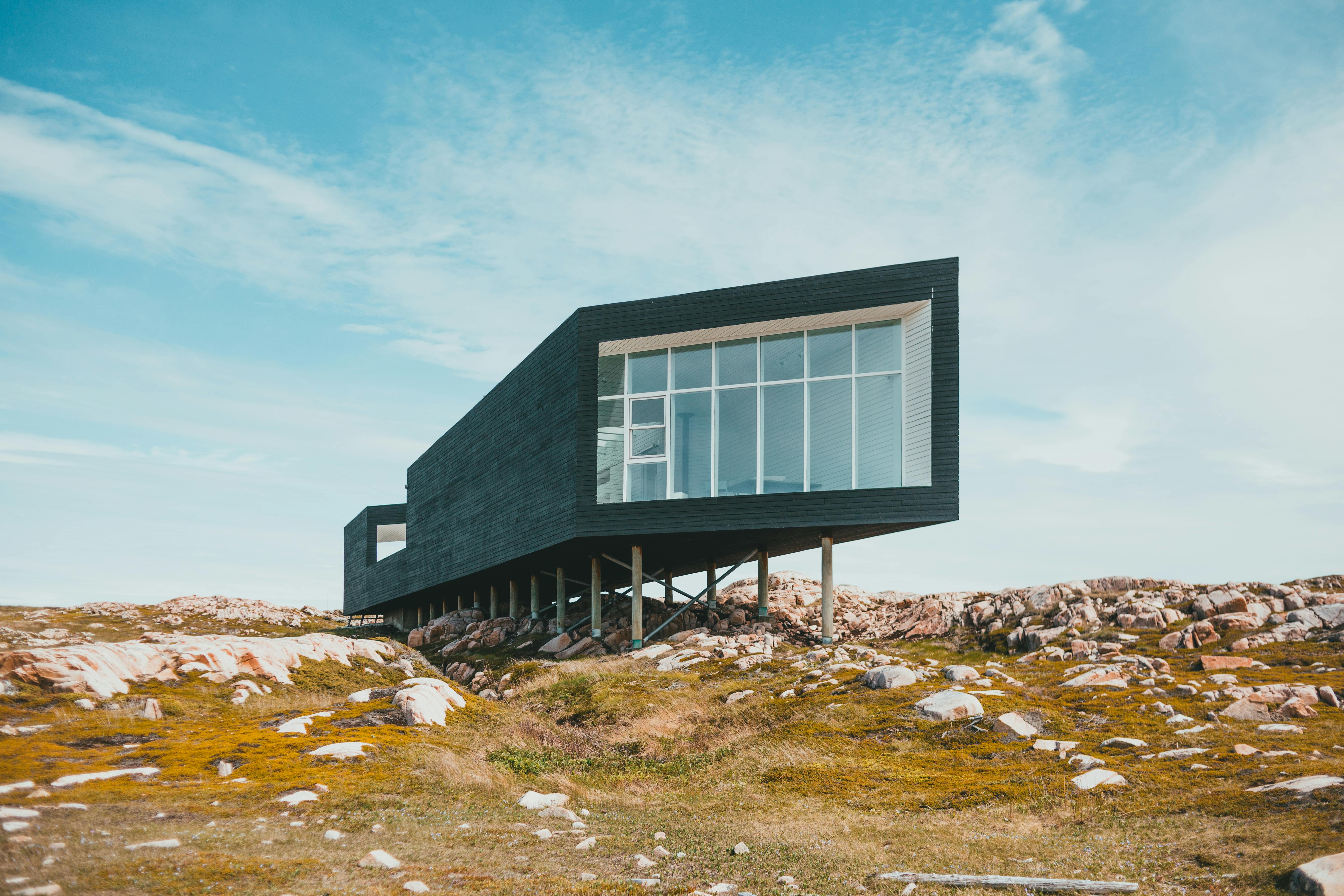Narrow modern tiny house exterior in rugged coastal setting.