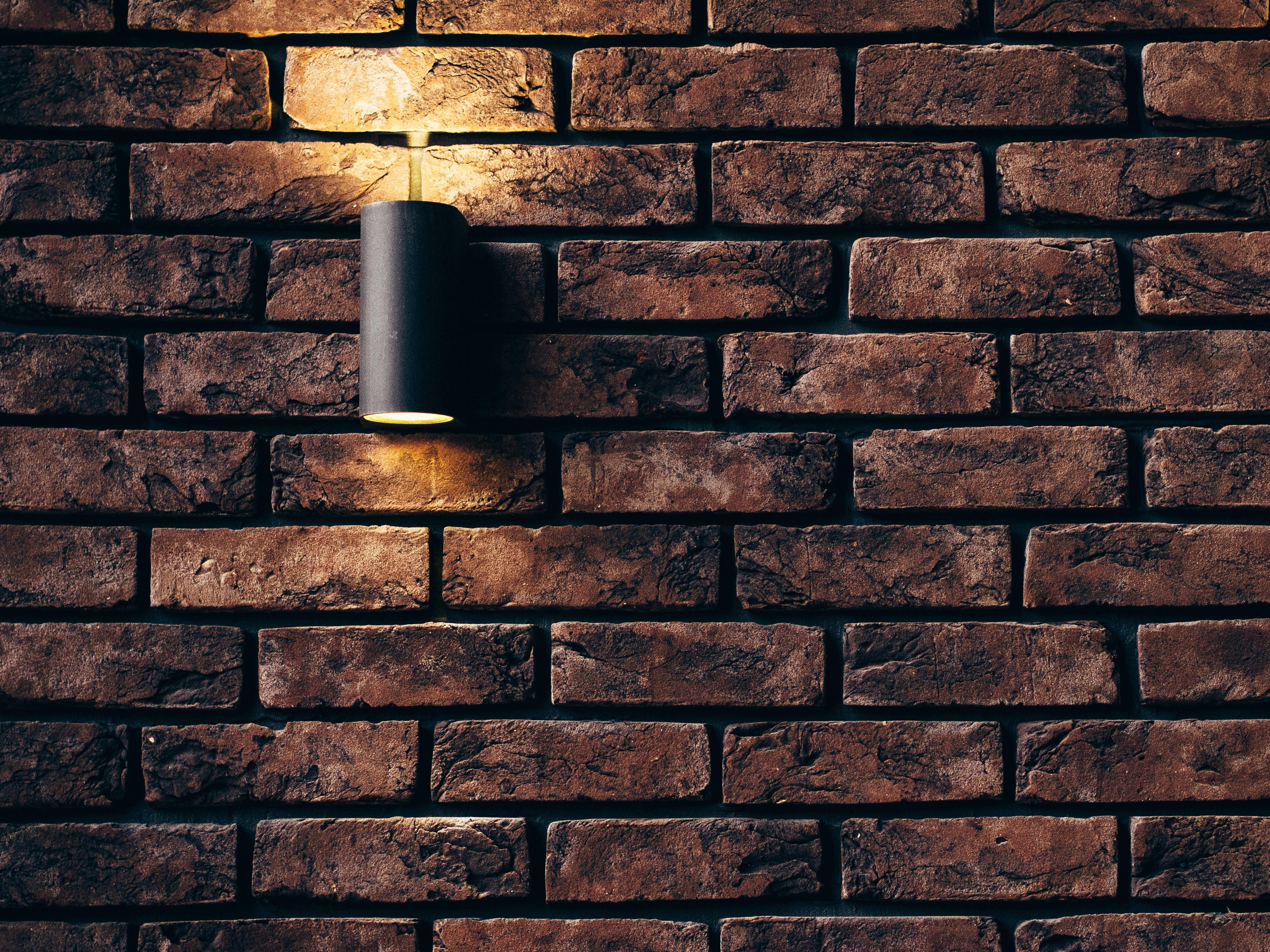 Exterior stone wall with black tubular light fixture.