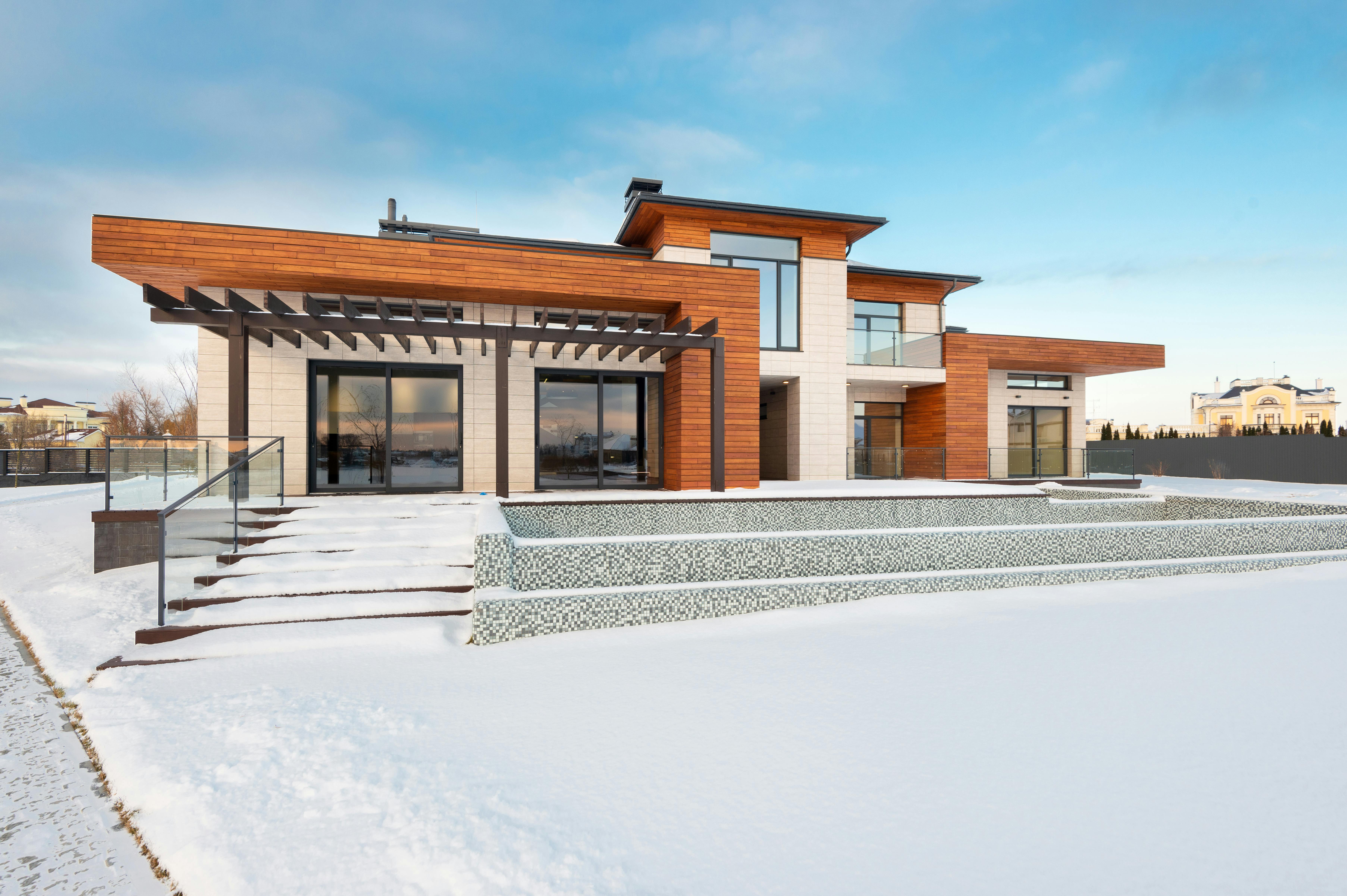 Facade of a modern suburban mansion combining stone and wood materials.