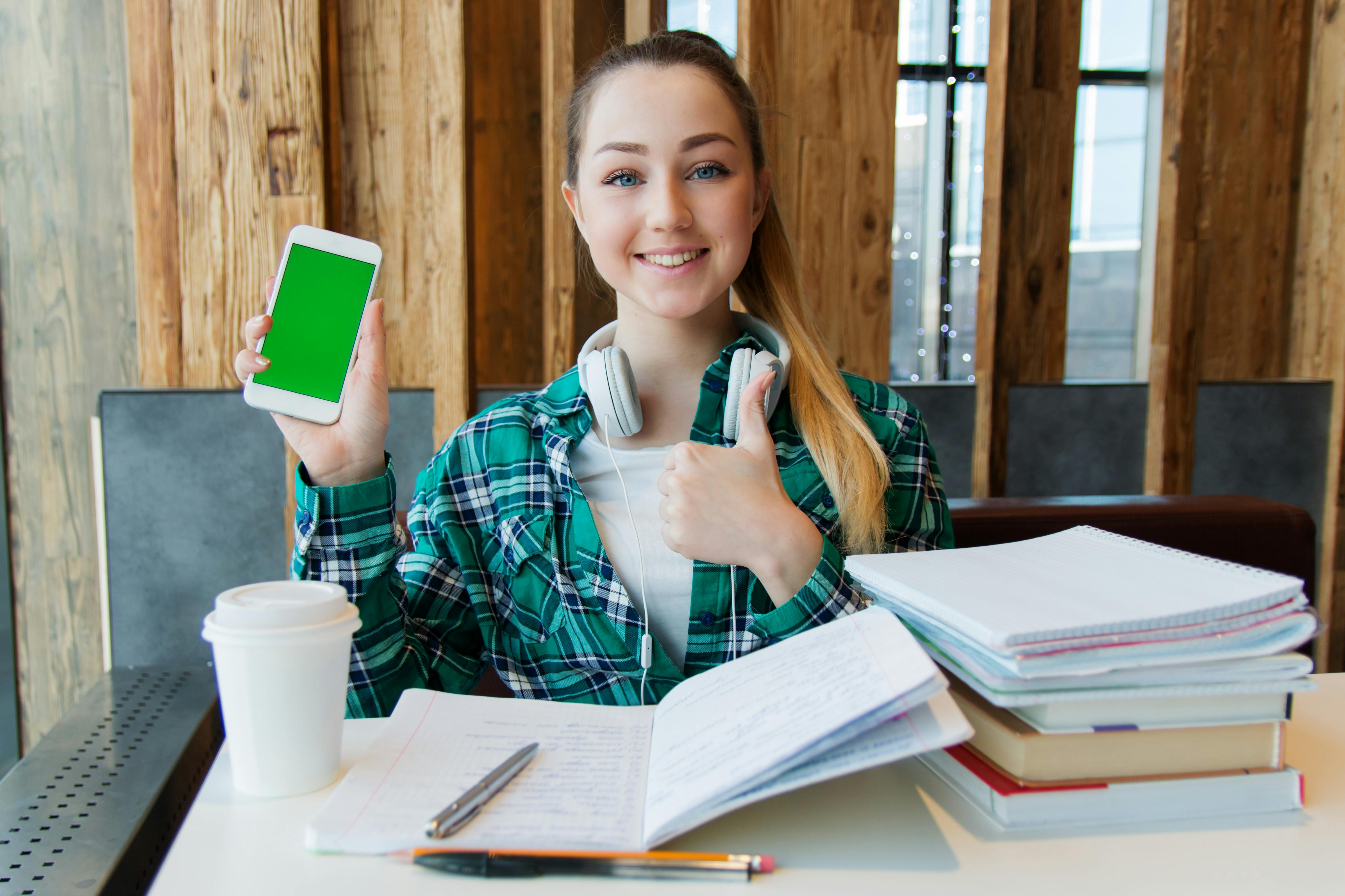 Female student studying architecture using phone and books in library.