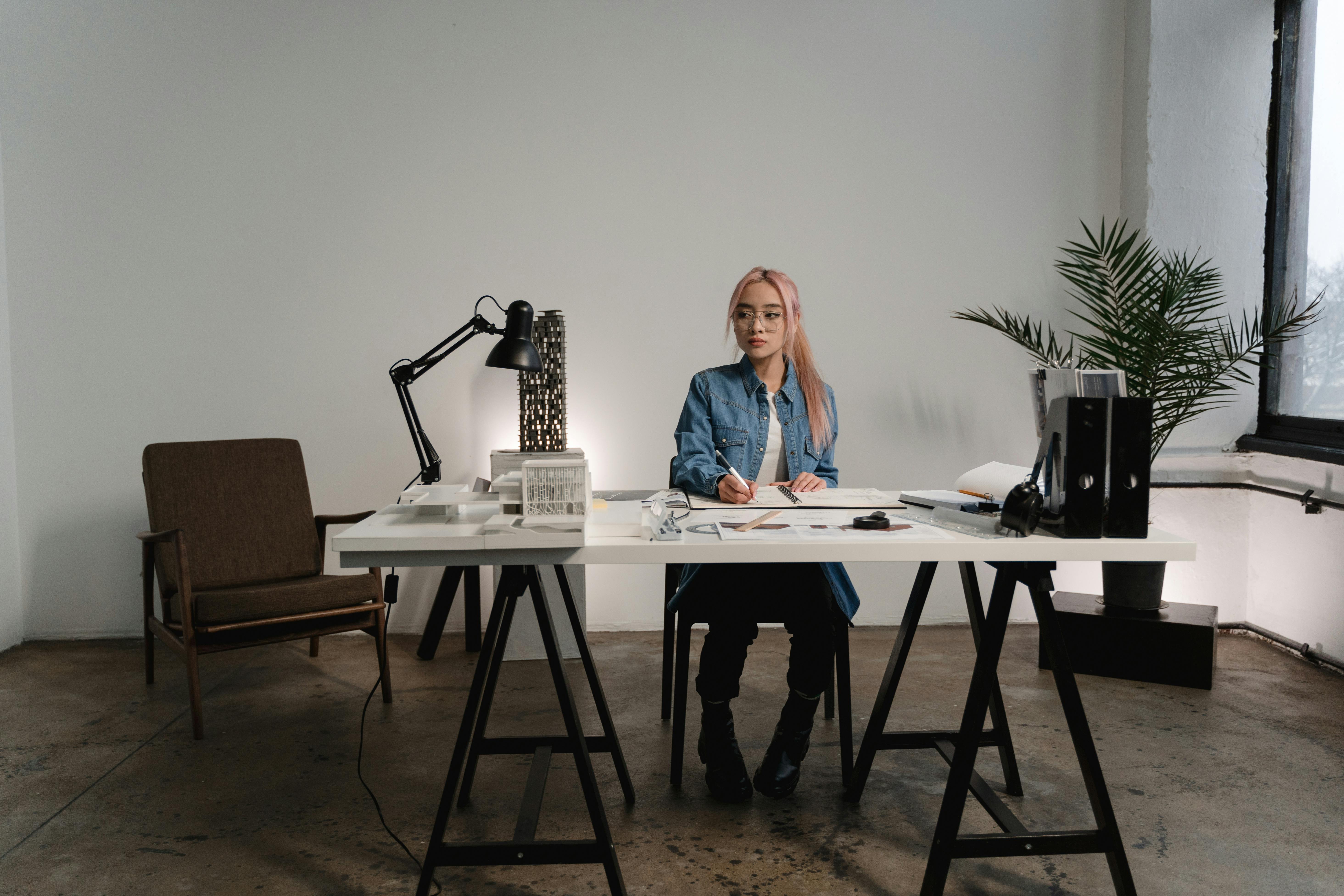Architecture student in modern workspace studying traditional model amid advanced tools.
