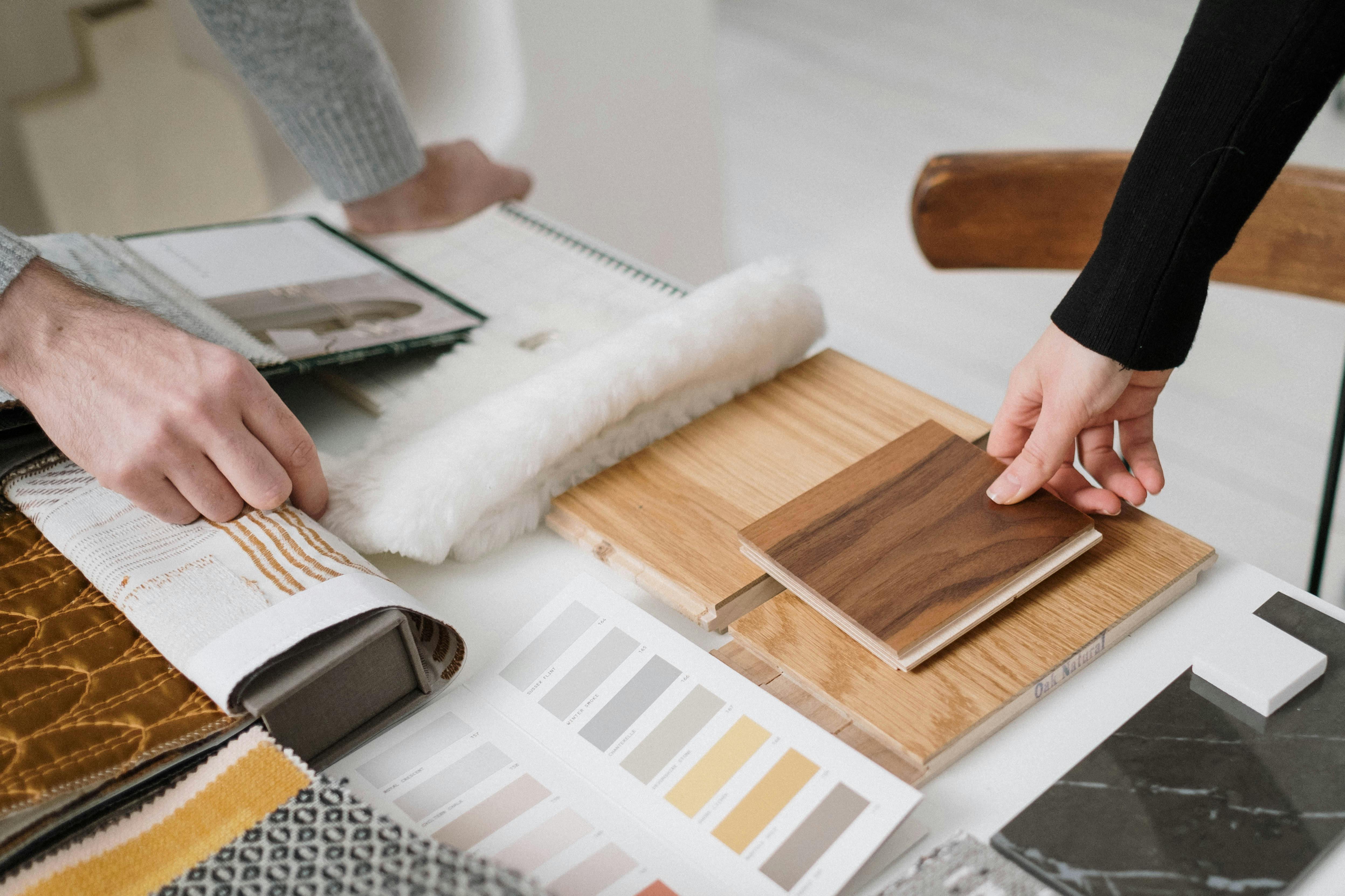 Close-up of a hand holding various wooden plank samples—used in architectural material selection with a focus on design quality and sustainability.