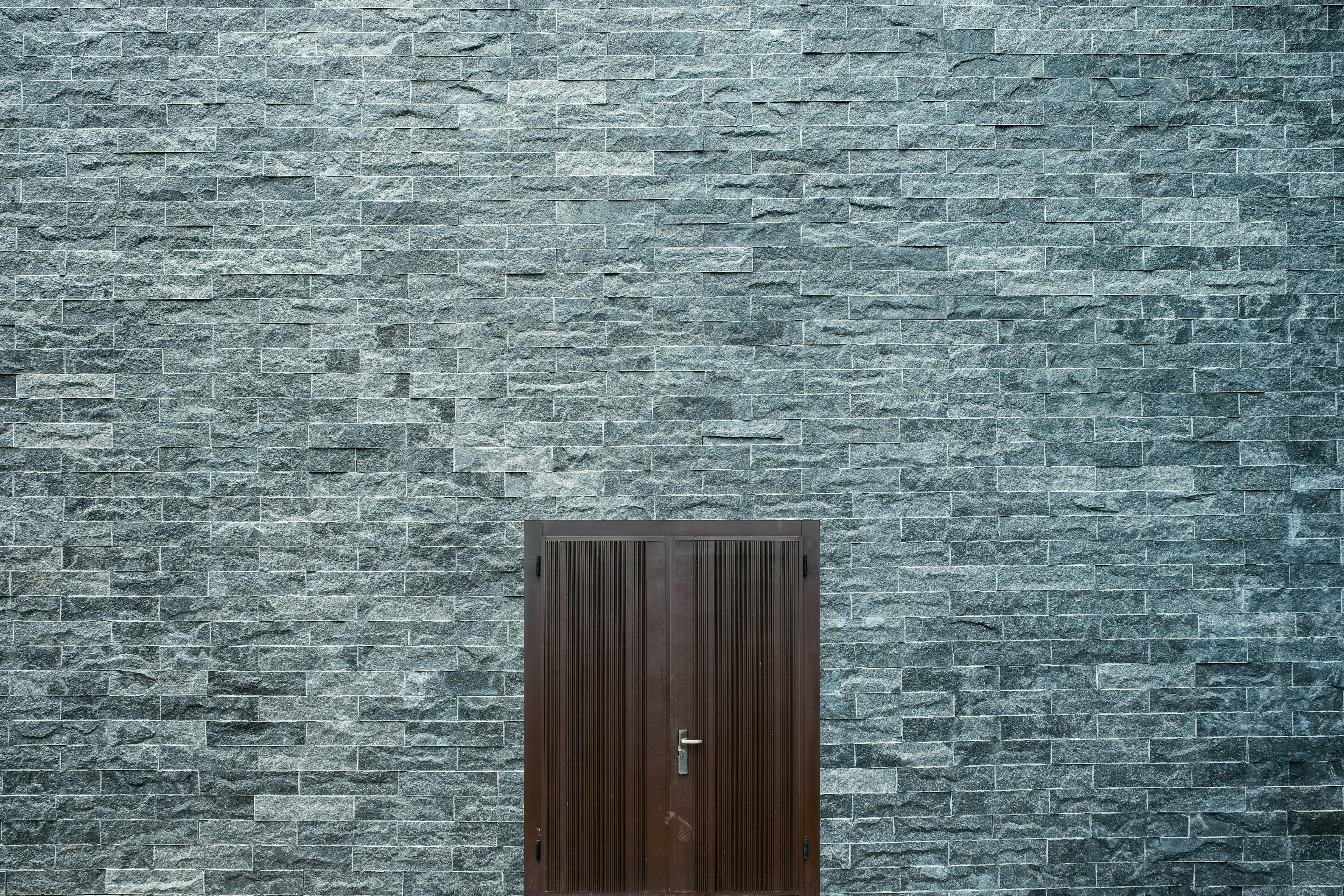 Brown wooden door set in a large flat brick wall.