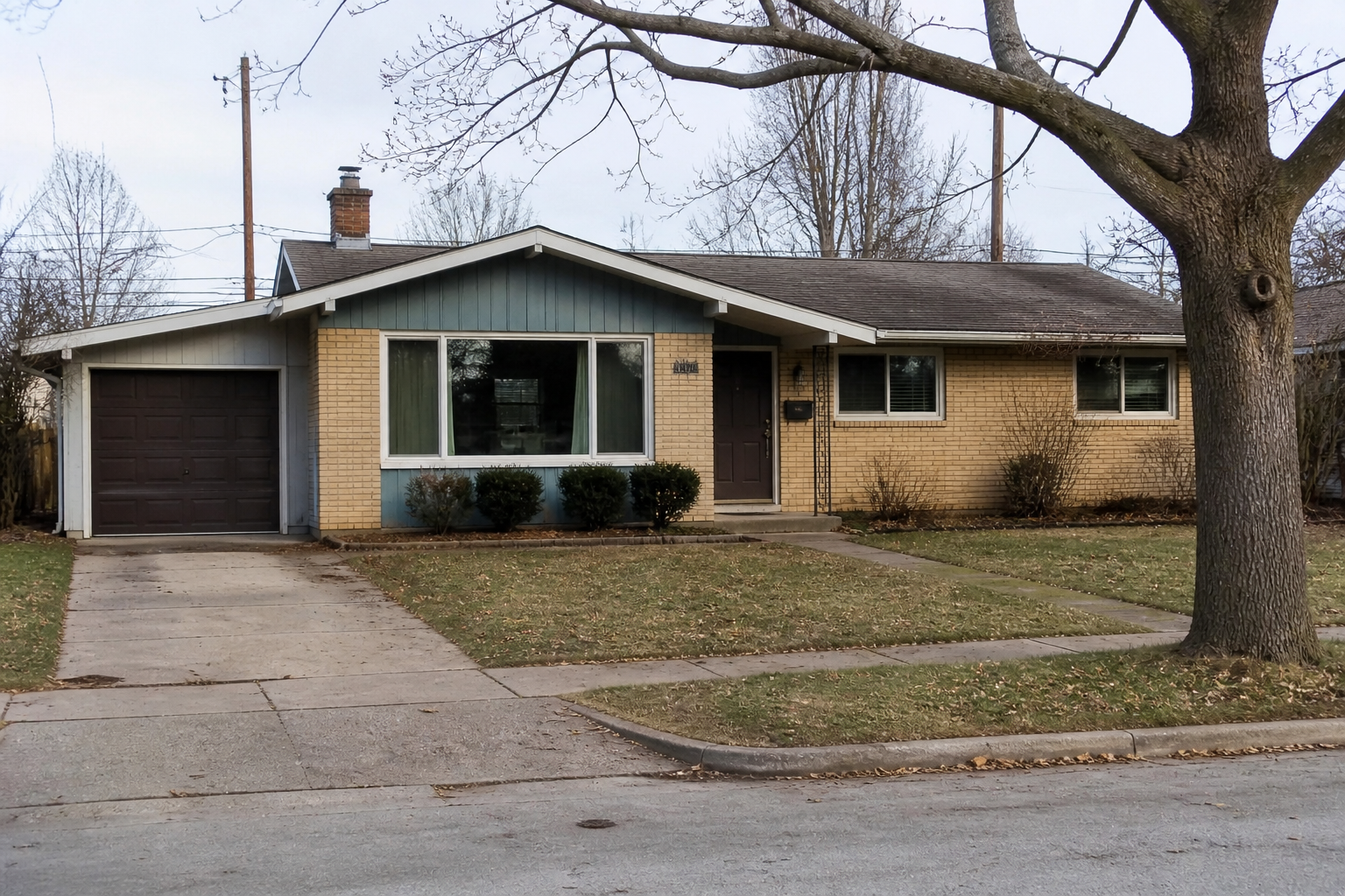 1950s ranch house with brick walls, low roofline, attached garage, and large front window.