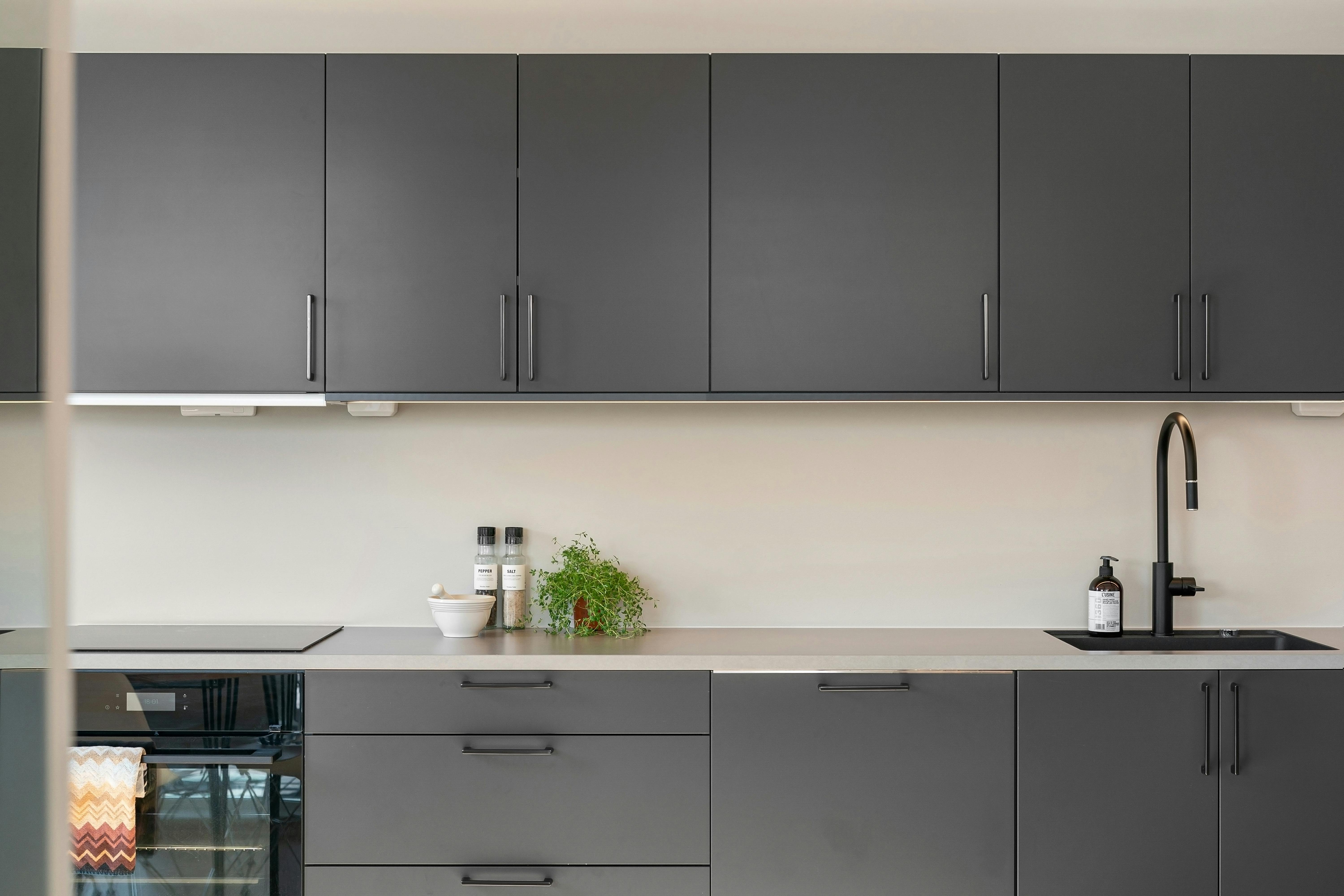 Kitchen with black cabinets, white walls, and white counter.