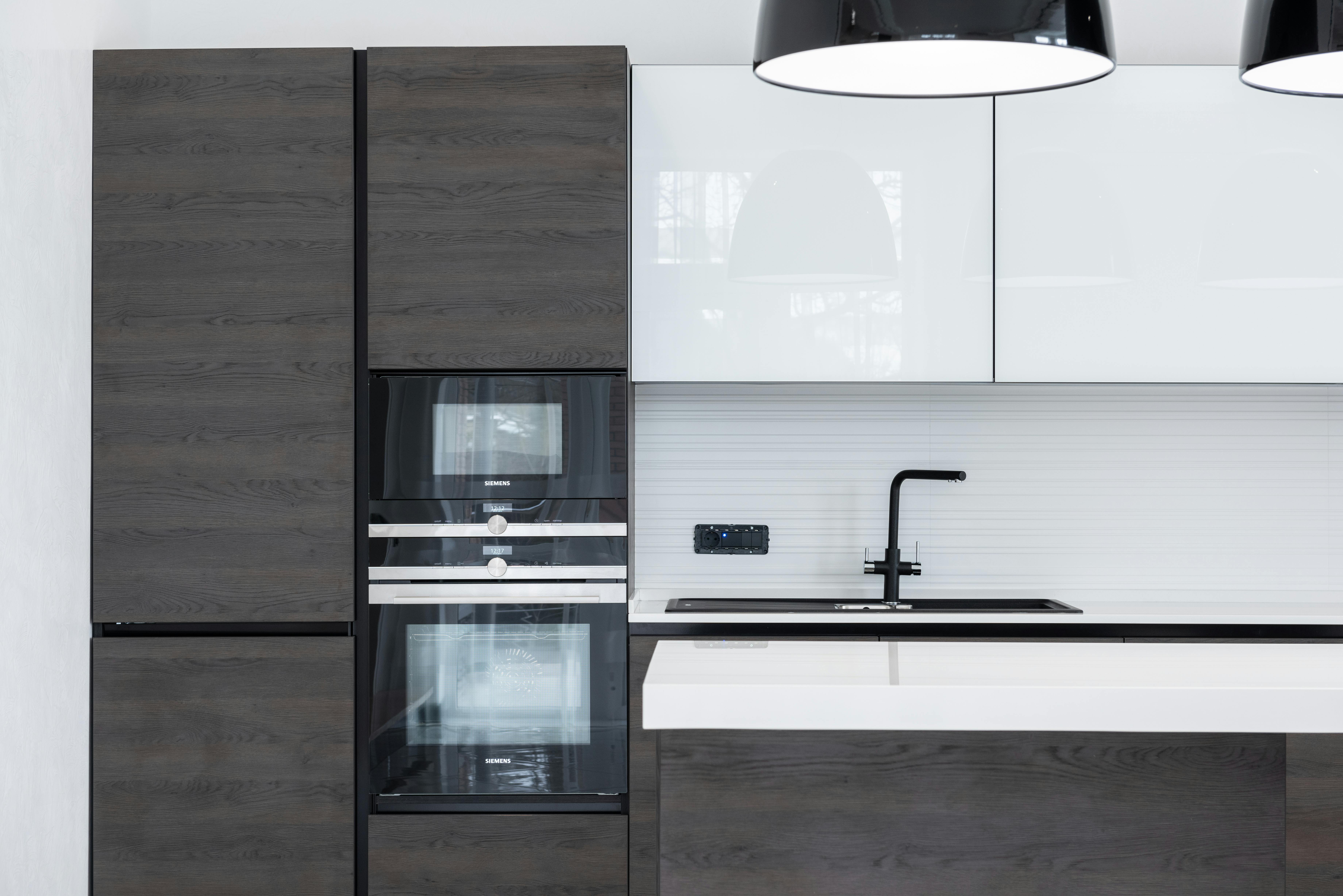 Modern kitchen with black cabinets and white counter.