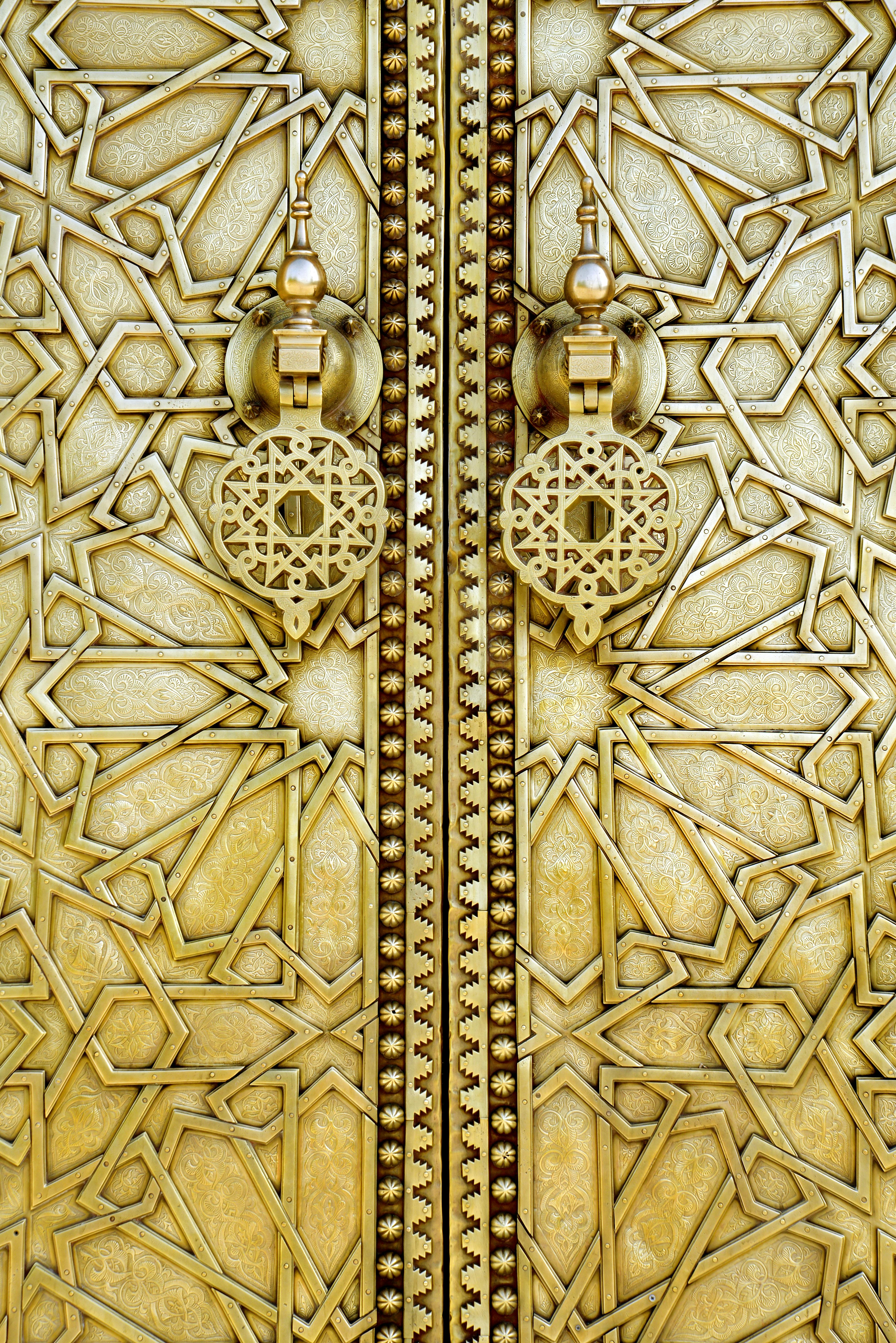 Ornate golden Islamic door with arabesque star patterns and decorative knockers.