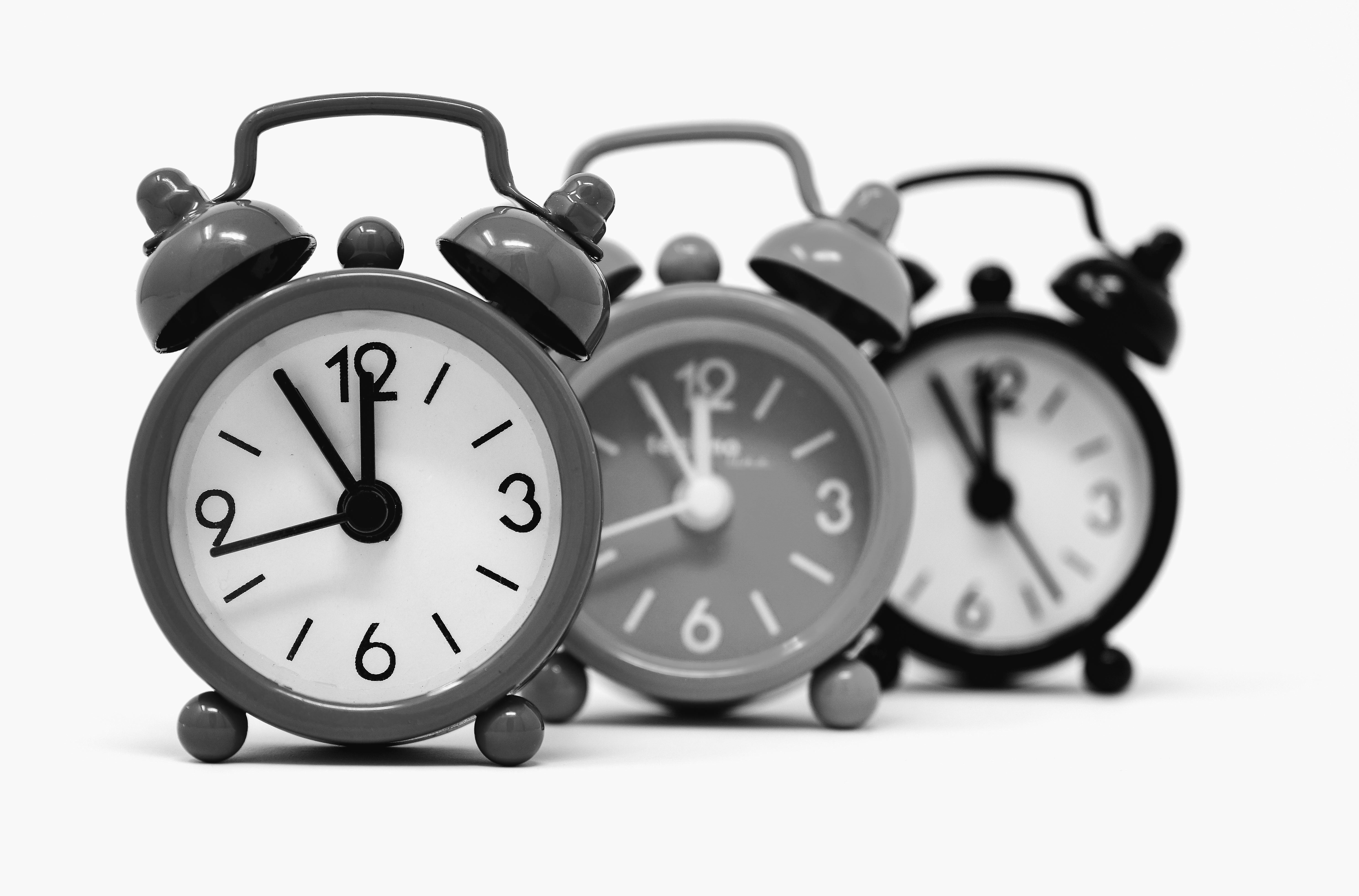 Architecture student adjusting a black twin-bell alarm clock.