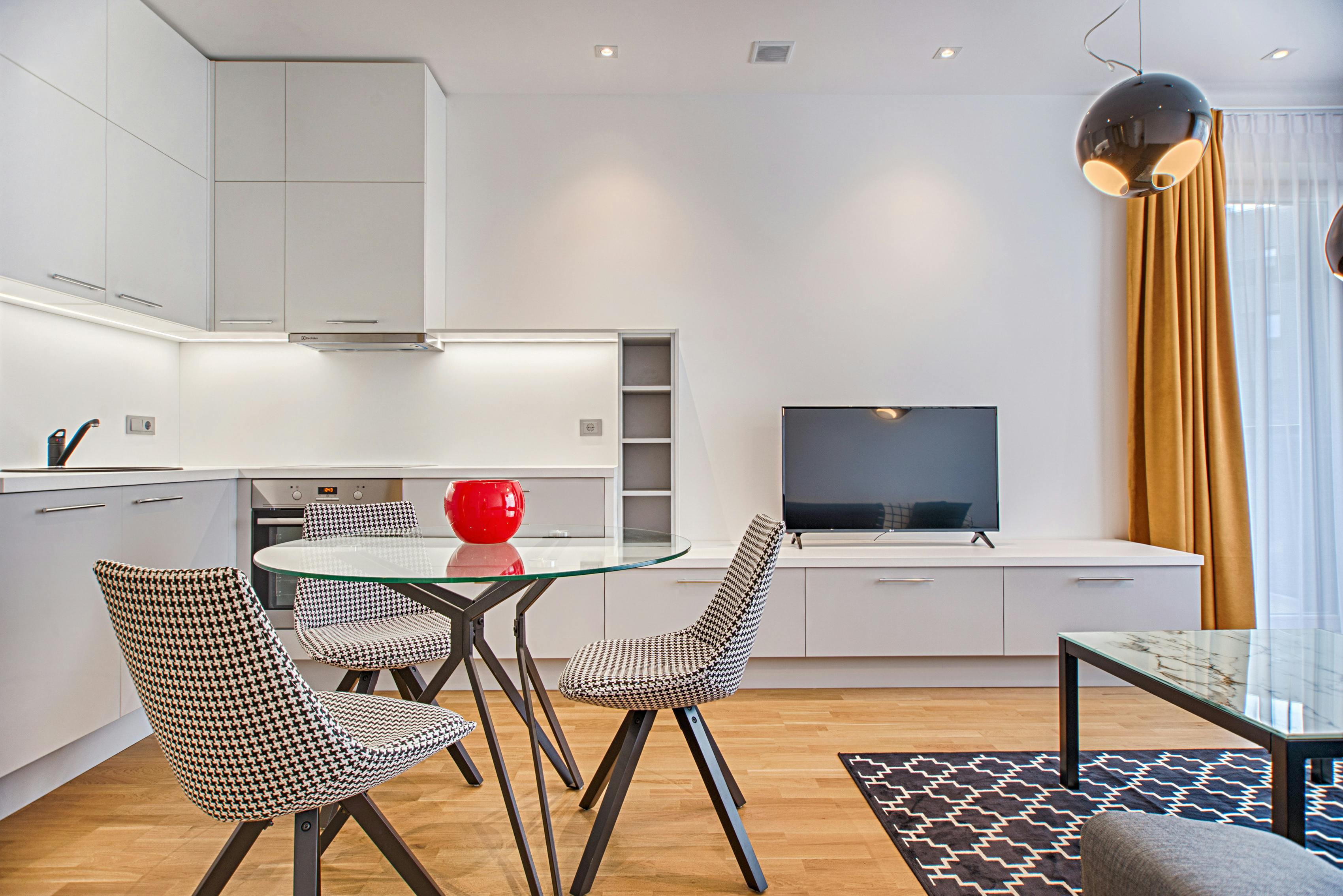 Example of minimalist interior design in a Vilnius living room, featuring two chairs, a glass table, and large windows that bring in natural light.