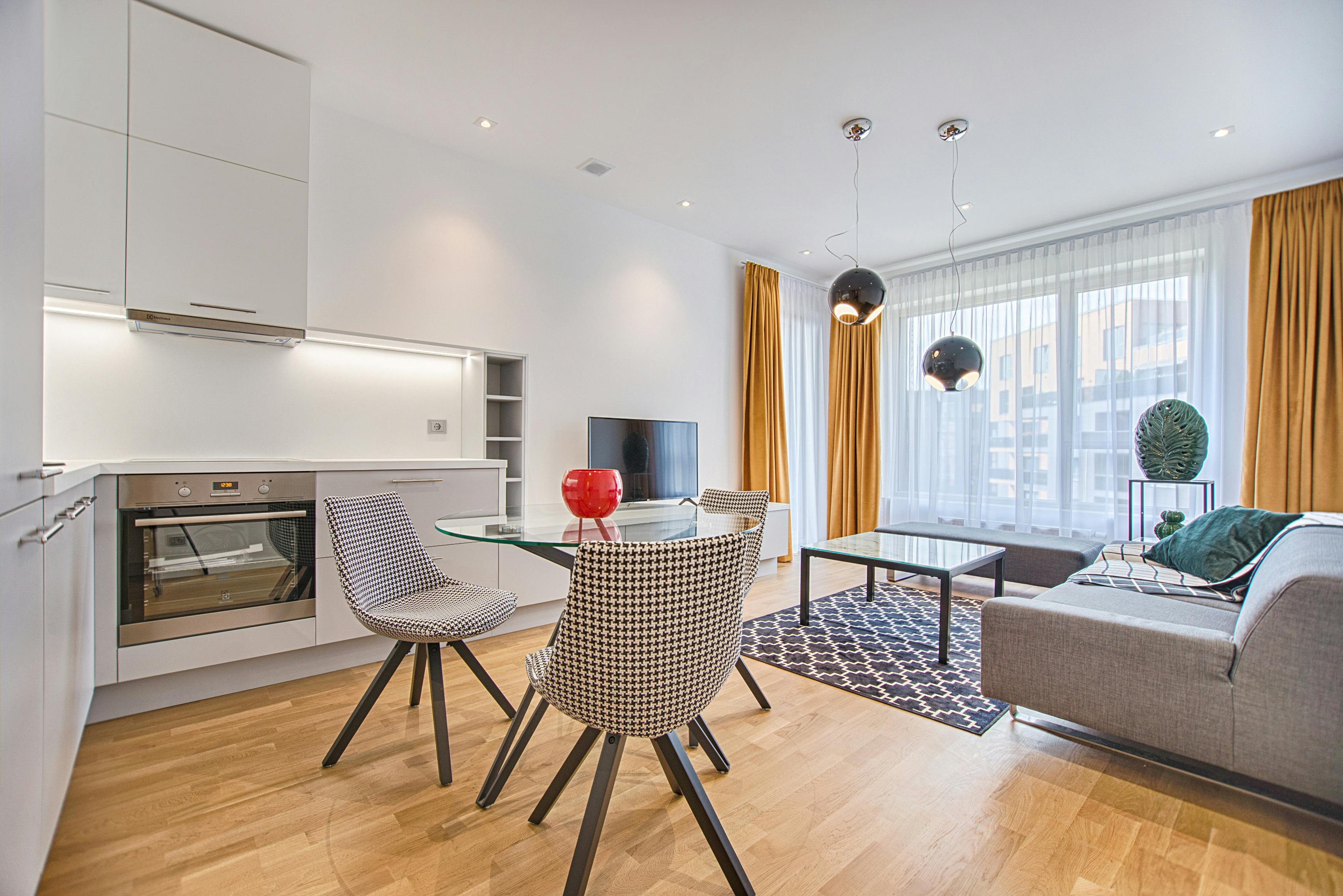 Two chairs and glass table in bright Vilnius living room.