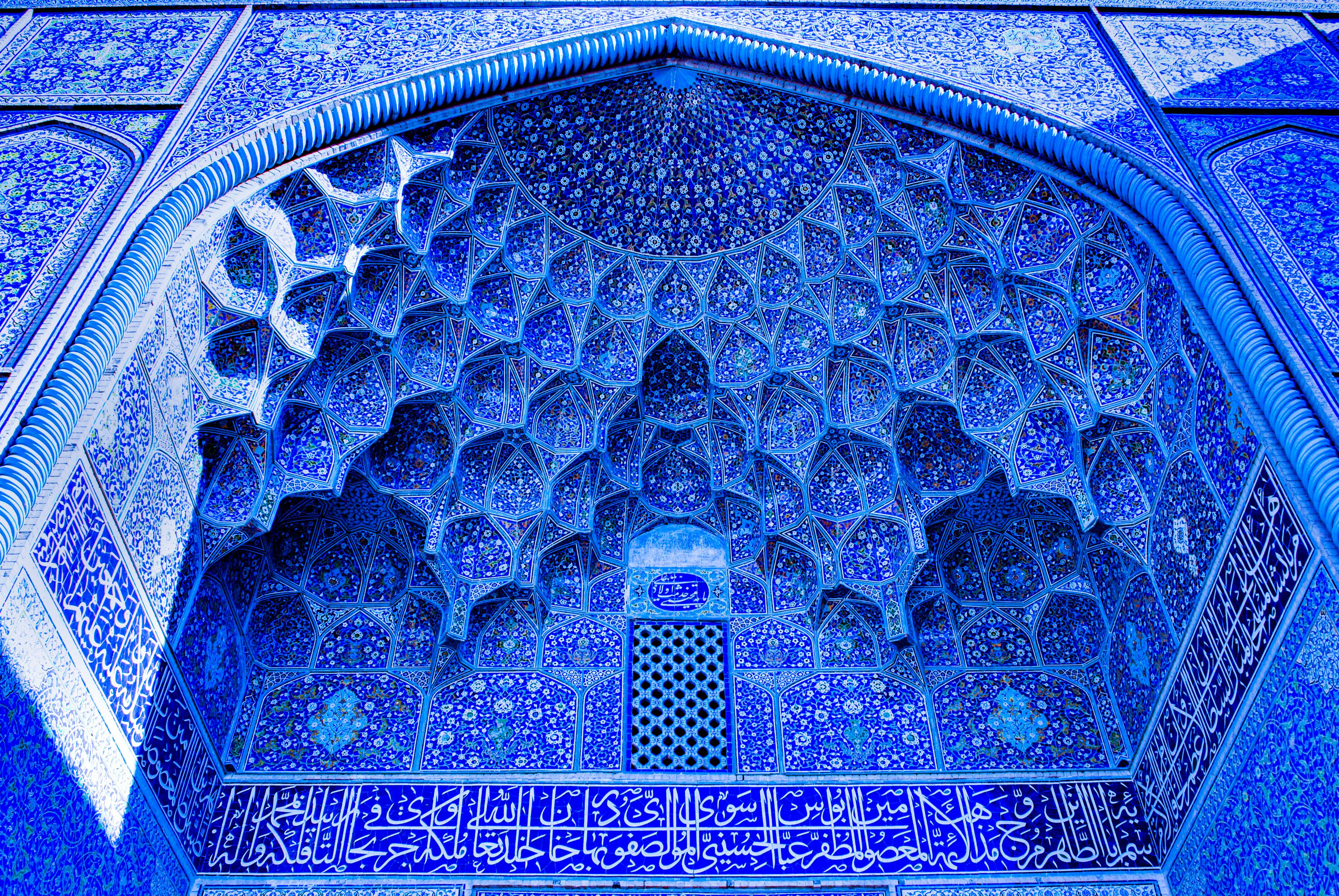 Shah Mosque exterior in Isfahan, Iran, with blue tiles and calligraphy.