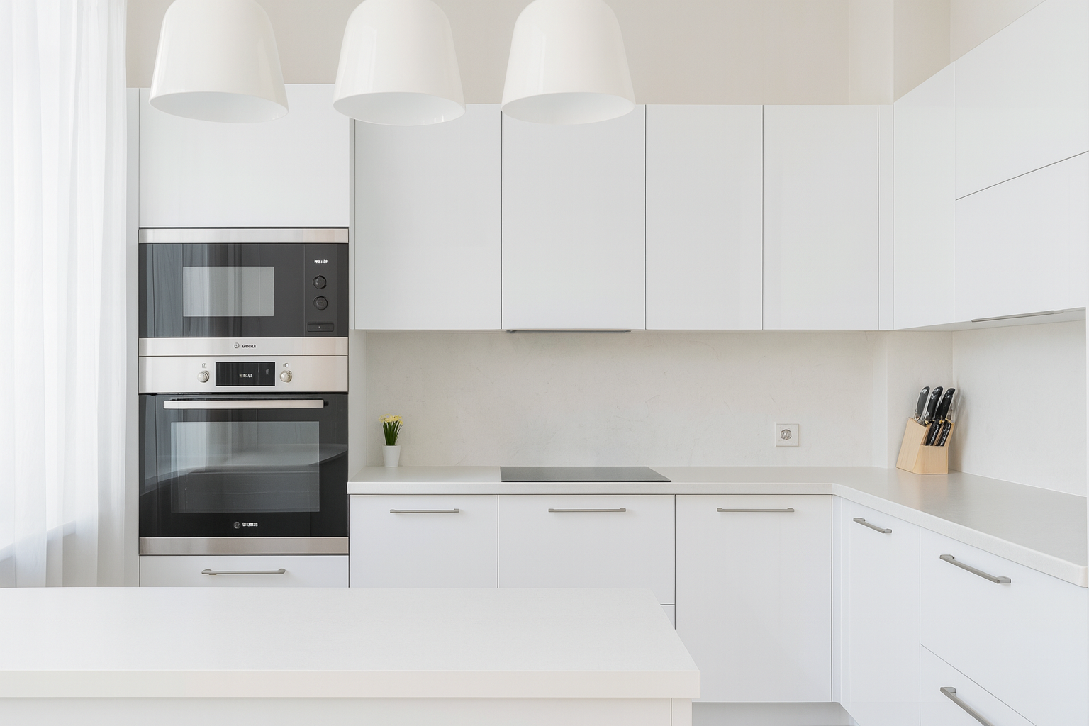 Modern kitchen with clean white cabinets, cool stone countertops, and stainless steel appliances.