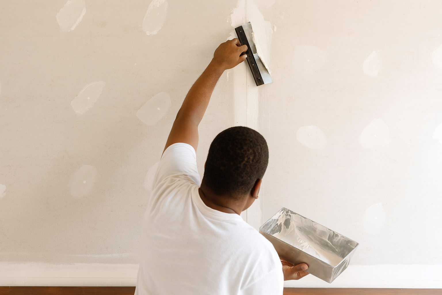 Construction worker applying joint compound to drywall seams.