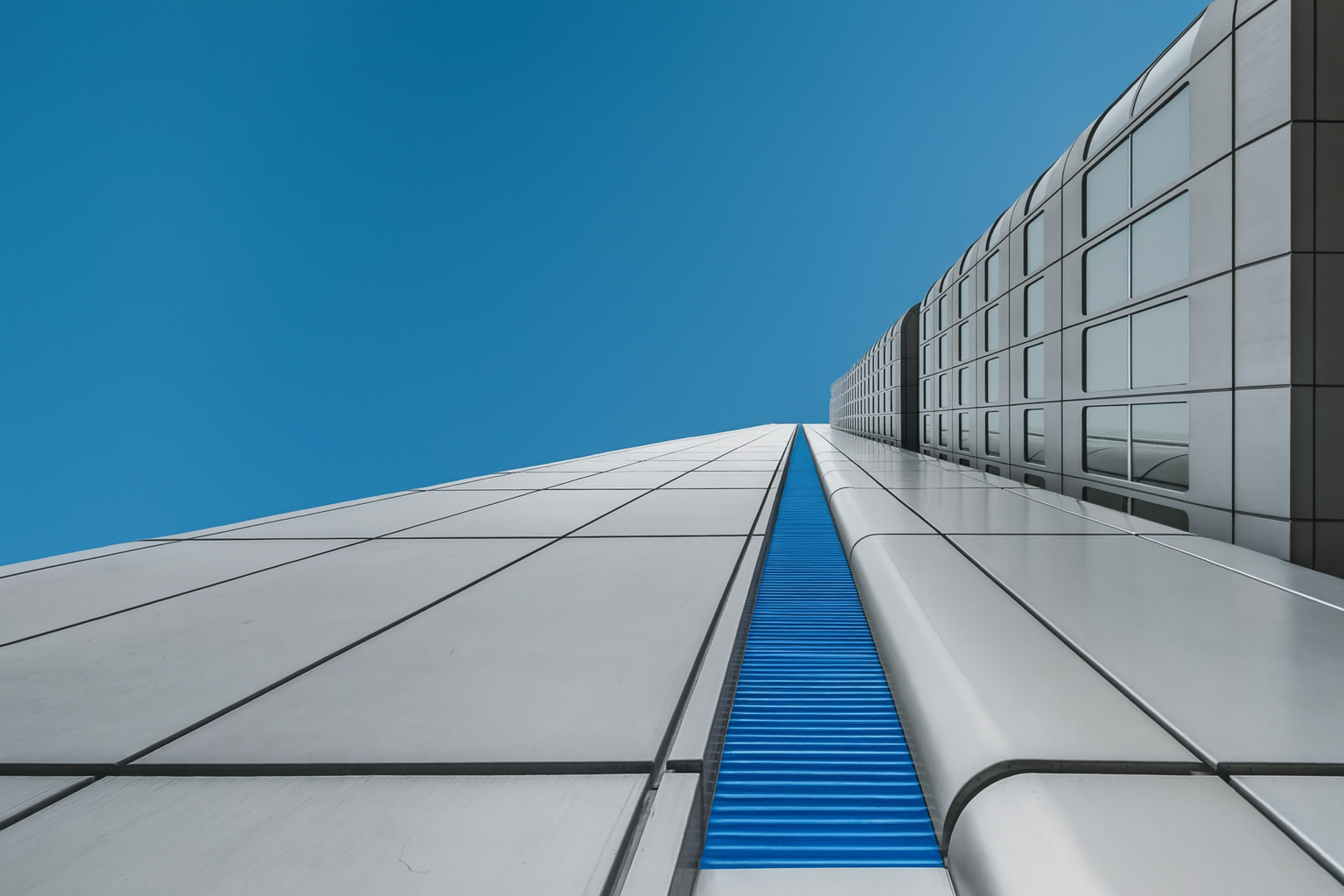 Contemporary skyscraper with reflective blue glass panels and sleek grey steel design.
