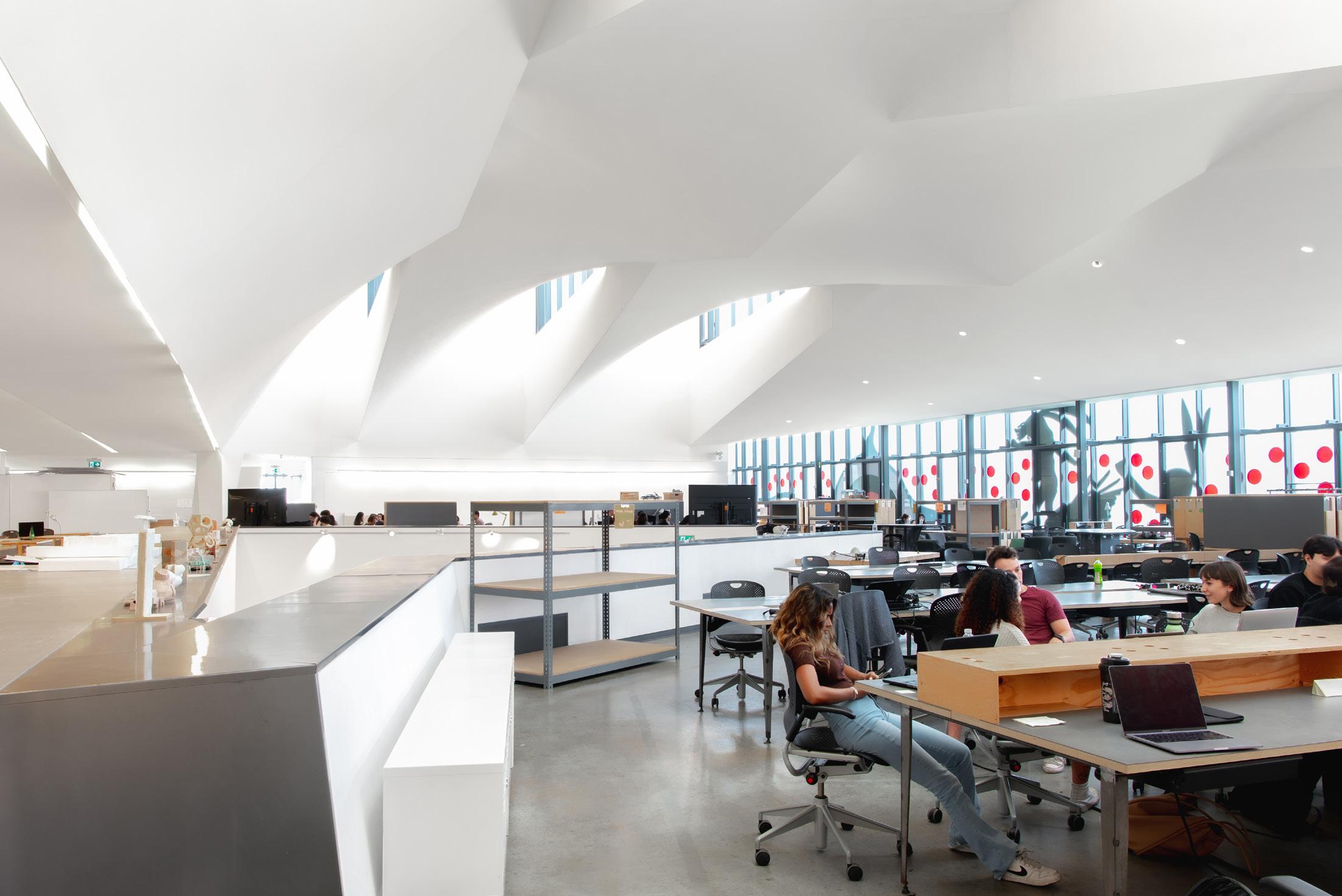 Interior of a modern university architecture studio with sculpted white ceiling and open workspace.