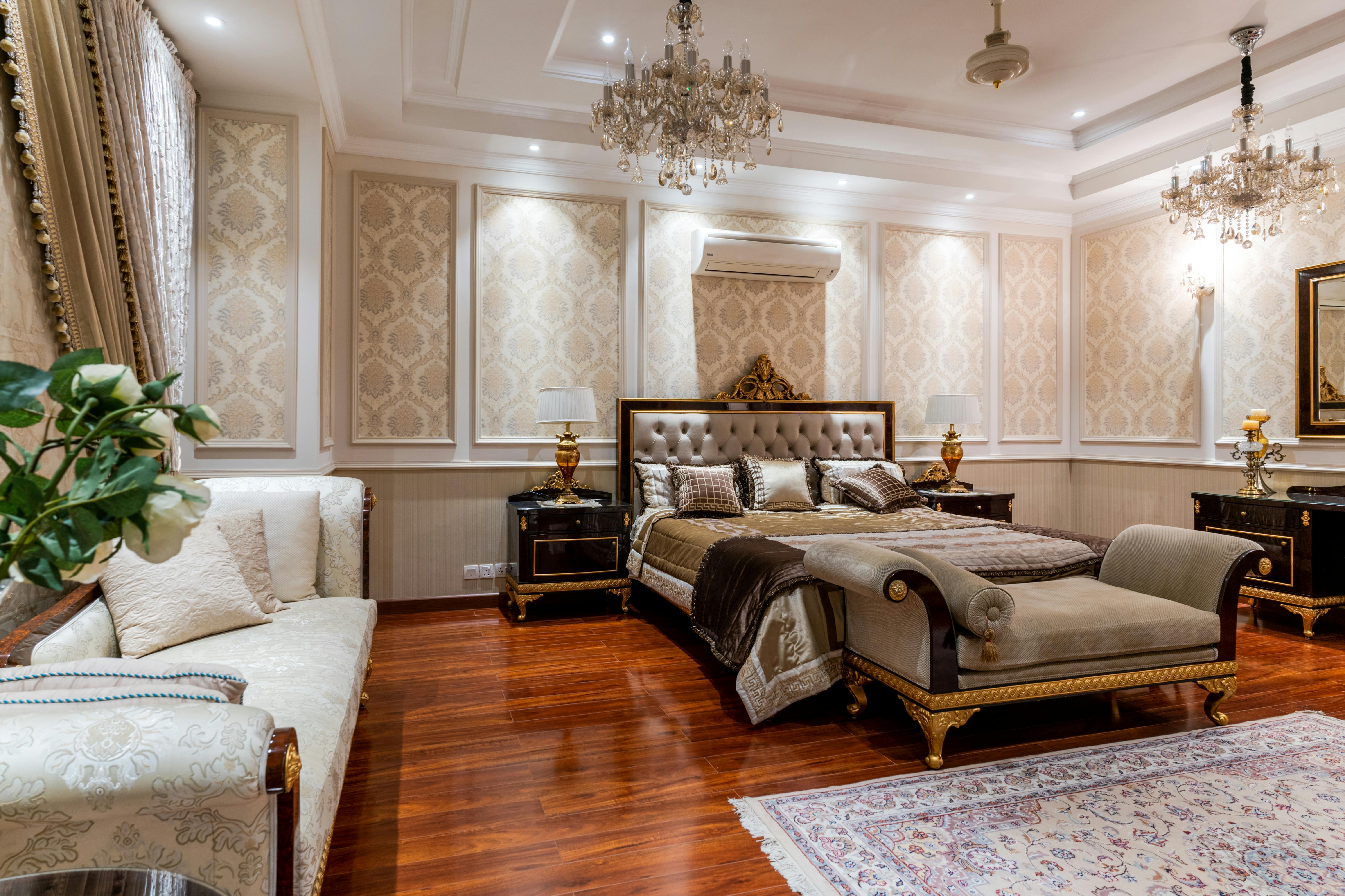 Luxurious traditional American bedroom with tufted headboard, crystal chandeliers, and gold-accented furniture.