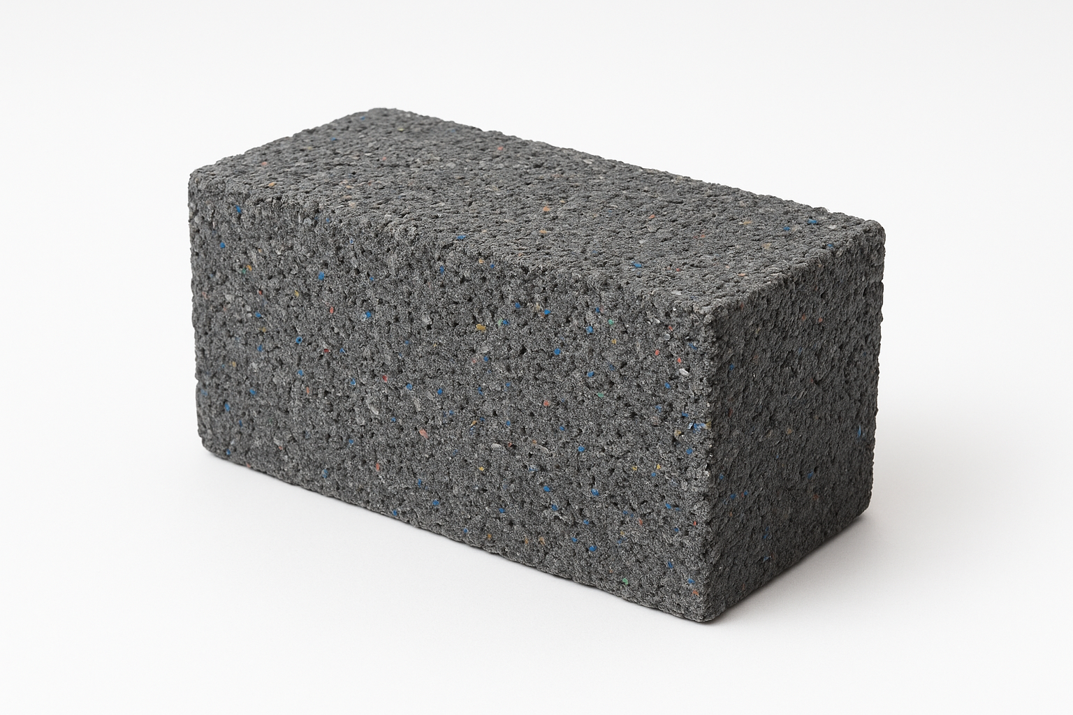 Recycled plastic brick with visible texture and multicolored flecks, showing sustainable construction material design.