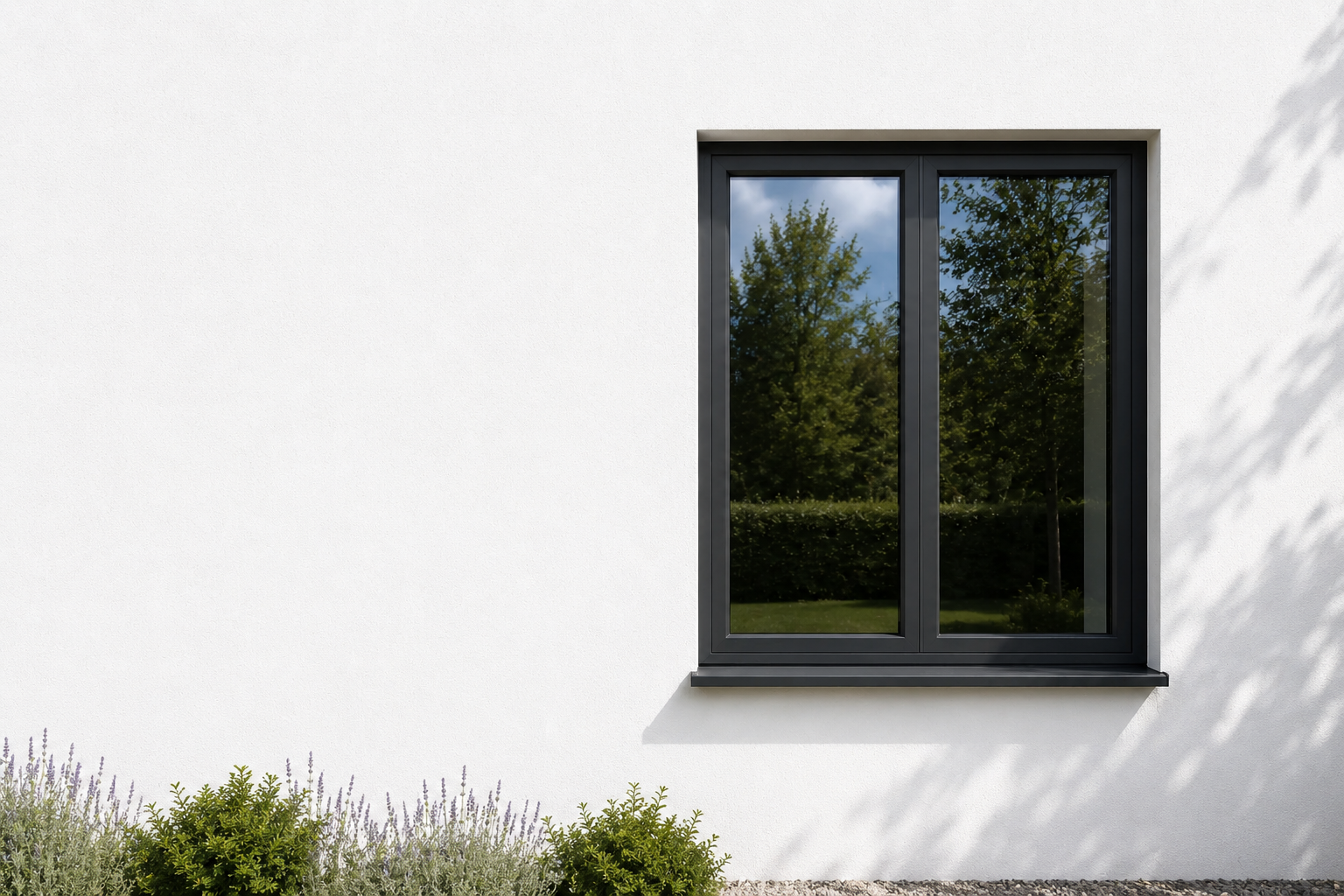 Black-framed window set into a white stucco exterior wall with reflected trees in the glass.