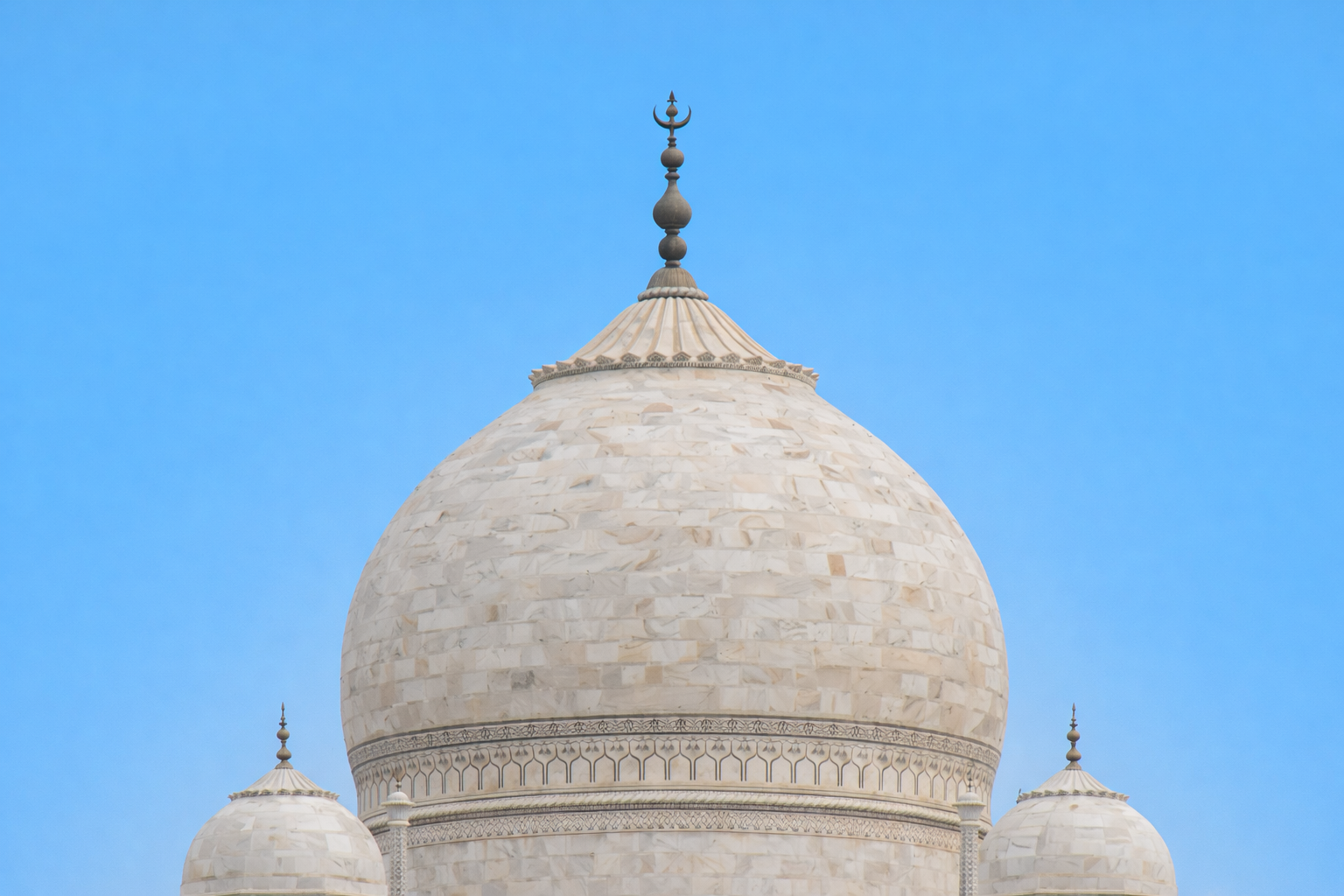 Close-up of the Taj Mahal’s onion dome showing marble coursing, drum banding, and the finial at the crown.