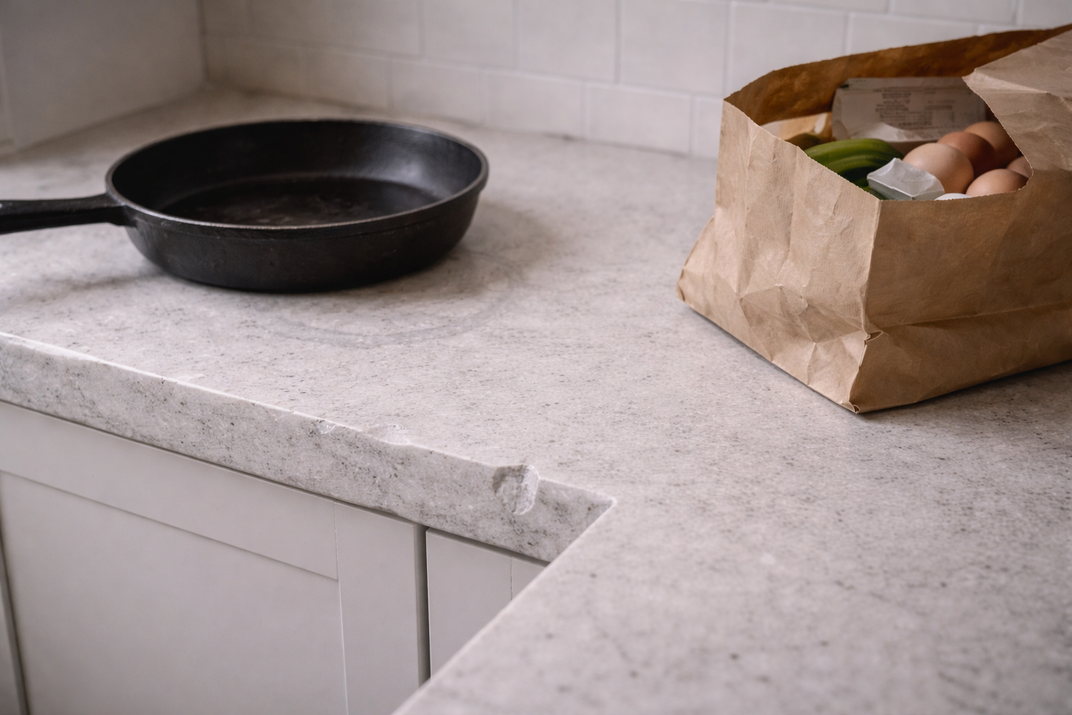 Hot pan and grocery bag showing real wear zone on kitchen benchtop.