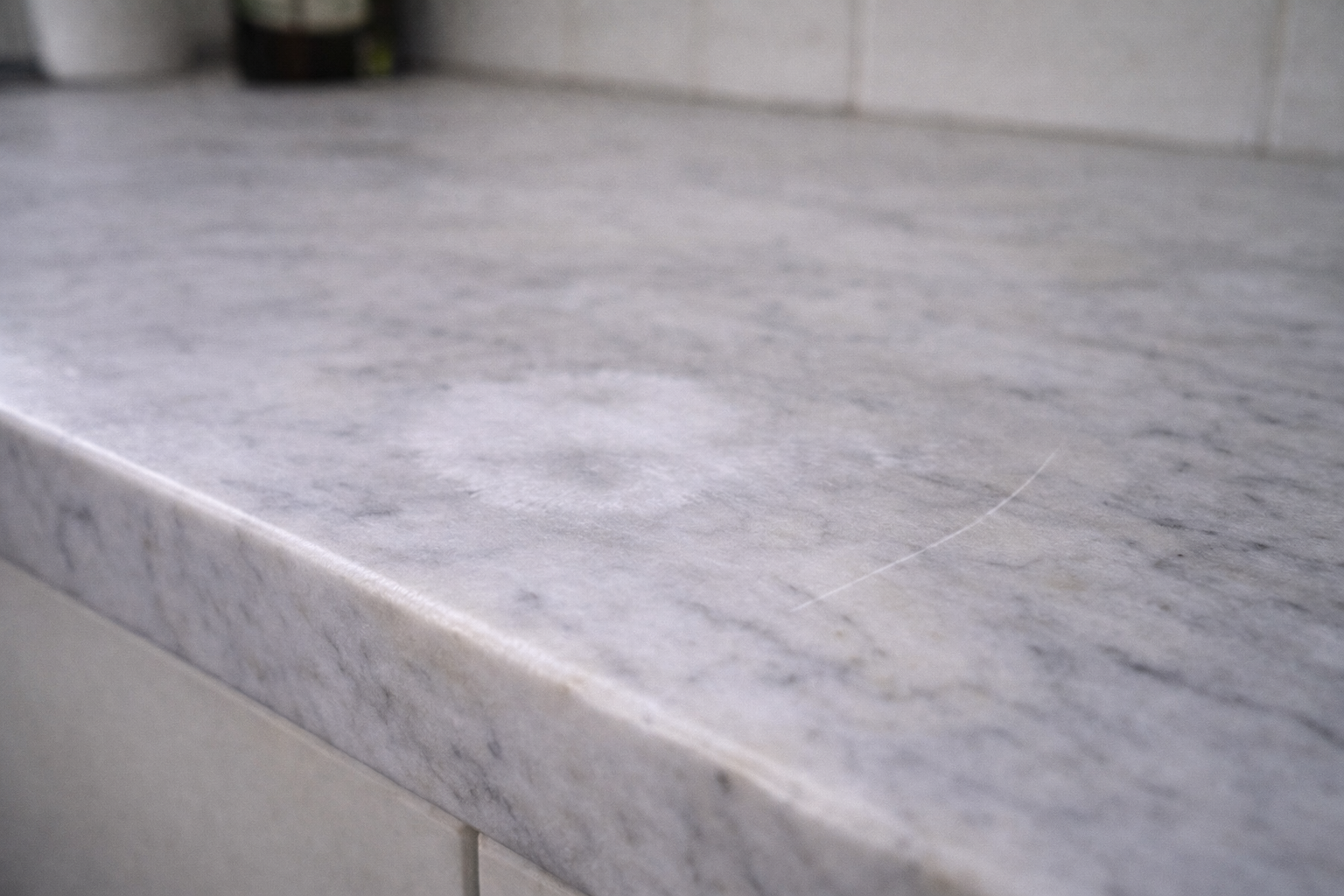Marble kitchen benchtop showing etching and a visible surface scratch from everyday use.