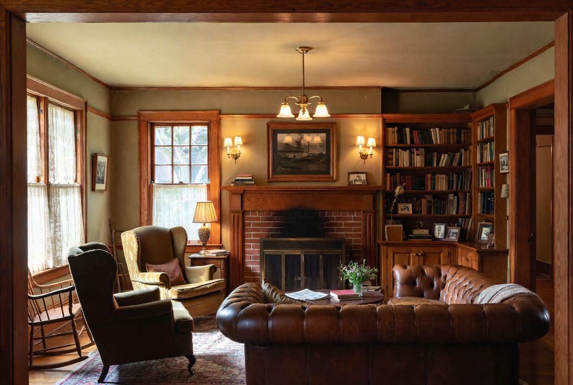 1920s living room with stained wood trim, brick fireplace, built-in bookcases, and warm layered lighting.