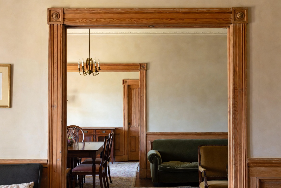 Interior opening with stained wood trim and connected rooms in a 1920s house.