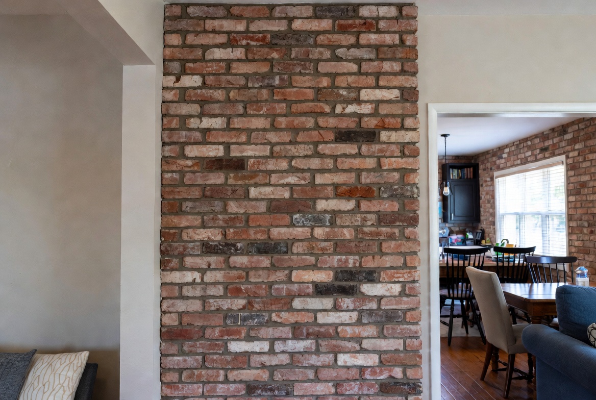 Aged thin brick veneer wall in everyday home dining area with lived-in feel.